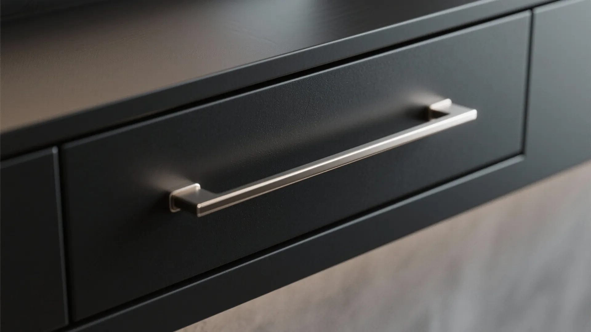Close up view of a black cabinet drawer with a slim silver metal pull handle