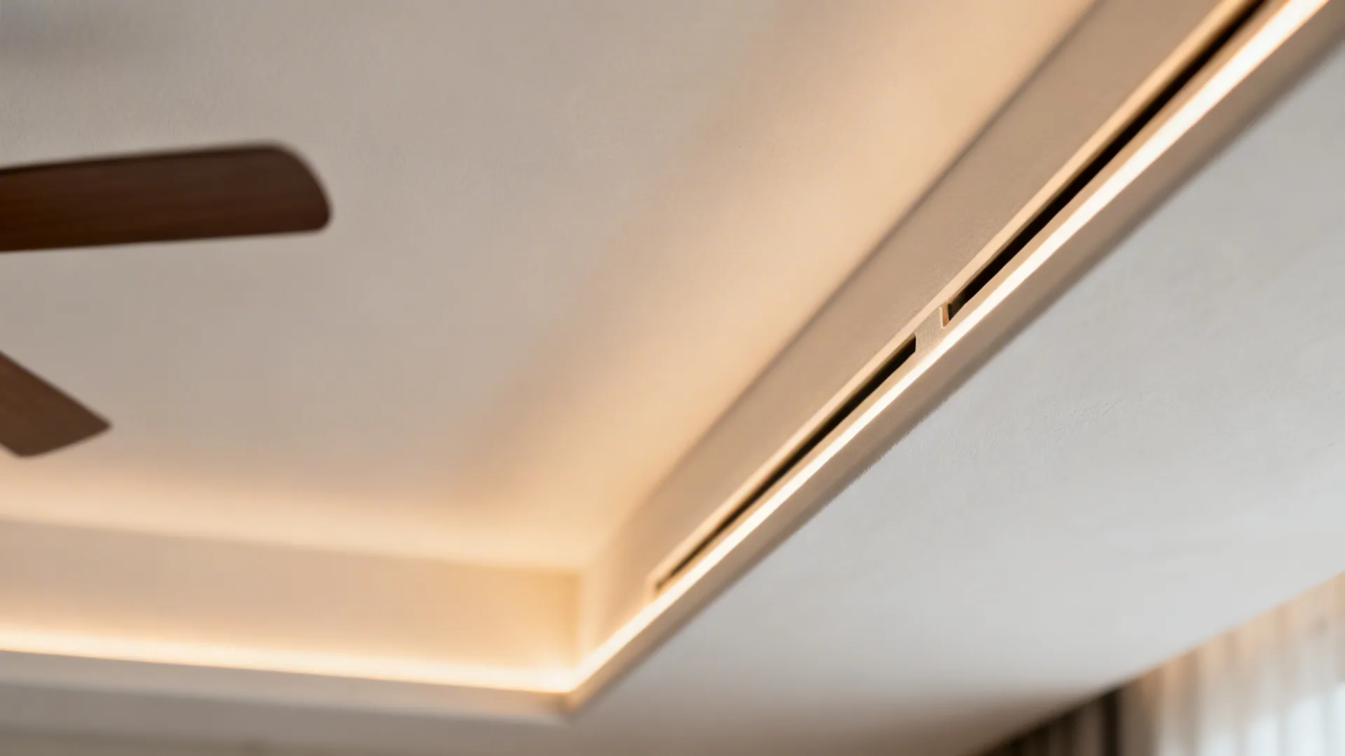 Macro of a linear slot diffuser and micro-cove in a seamless ceiling near an ultra-slim fan canopy.