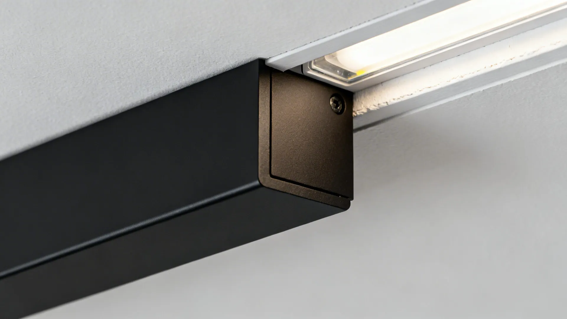 Macro of black linear slot diffuser and adjacent recessed LED line with crisp gypsum edge.