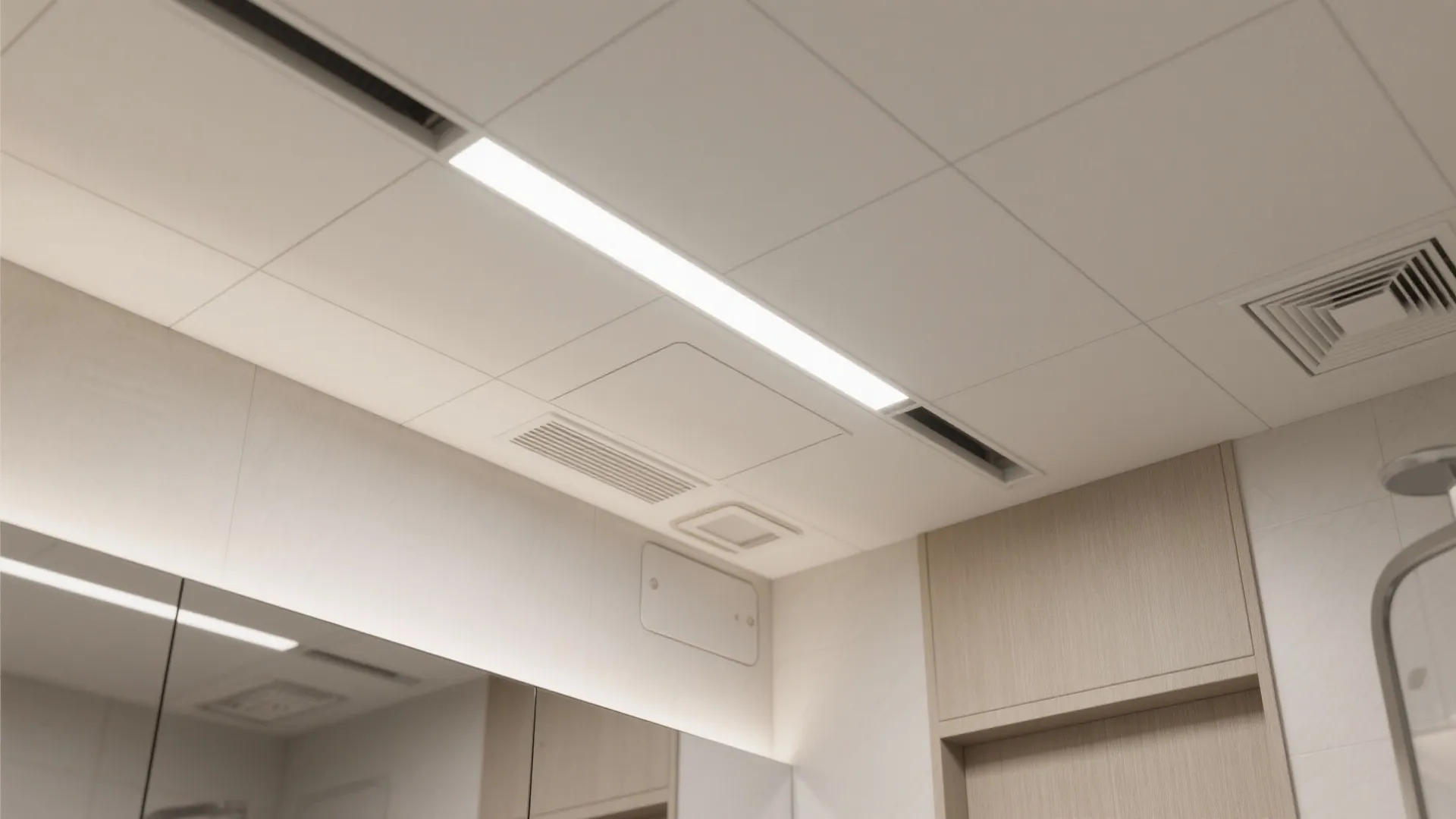 Tiled bathroom ceiling featuring a thin light fixture and square air vents in a grid