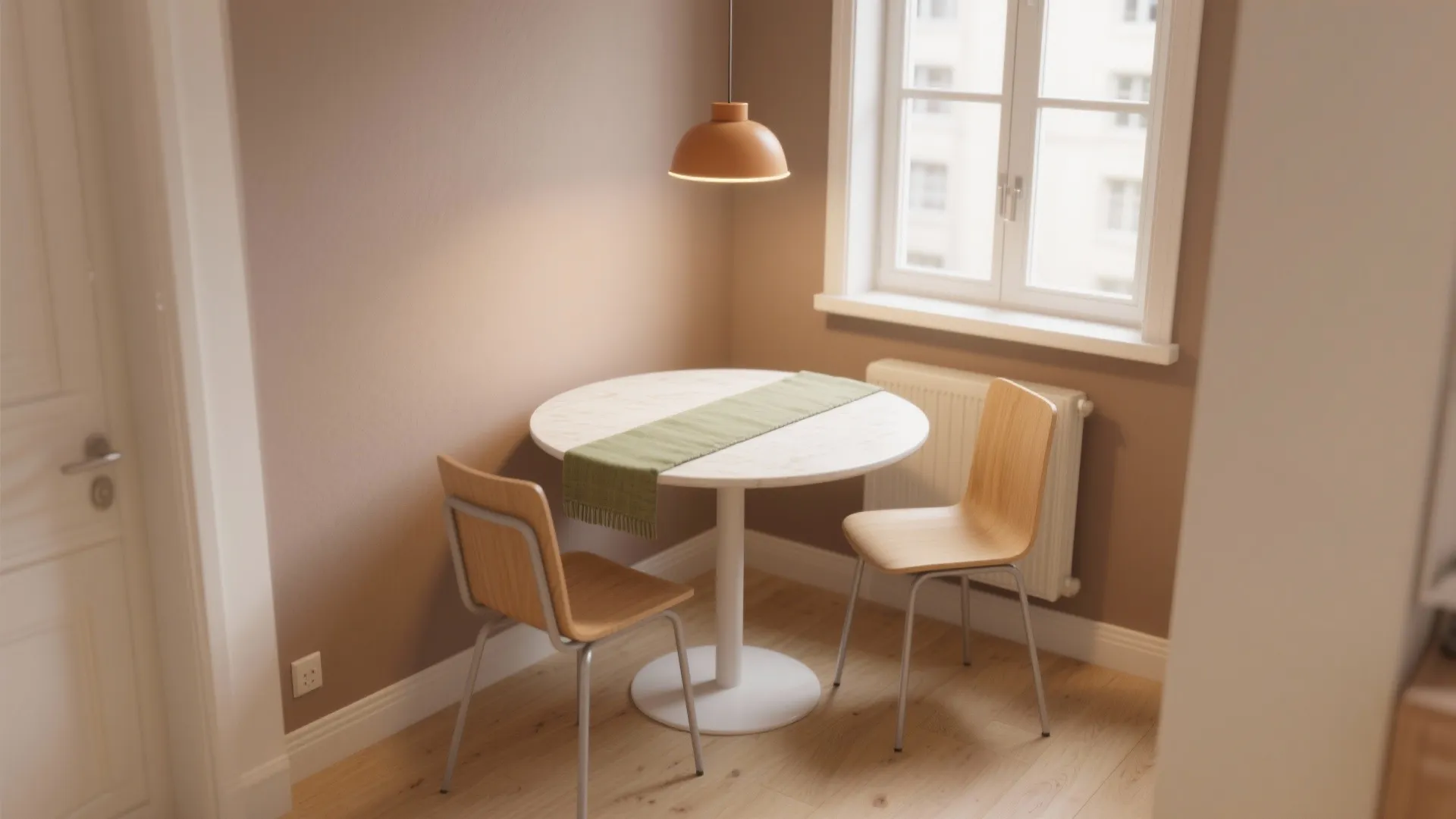Small round white table with two wooden chairs in dining corner with orange ceiling light
