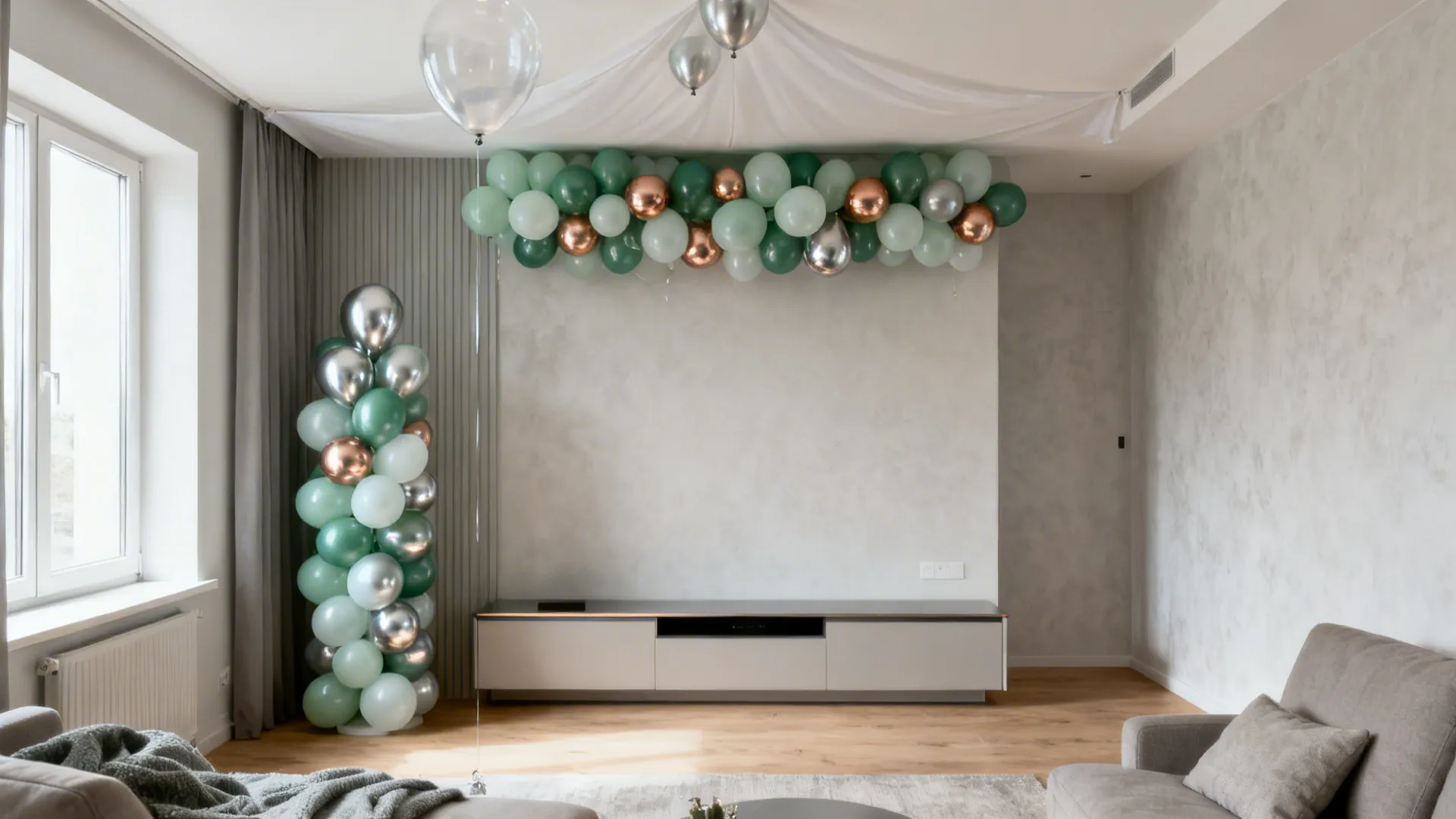 Living room with green and silver balloon arch, balloon column, grey sofa, and white wall