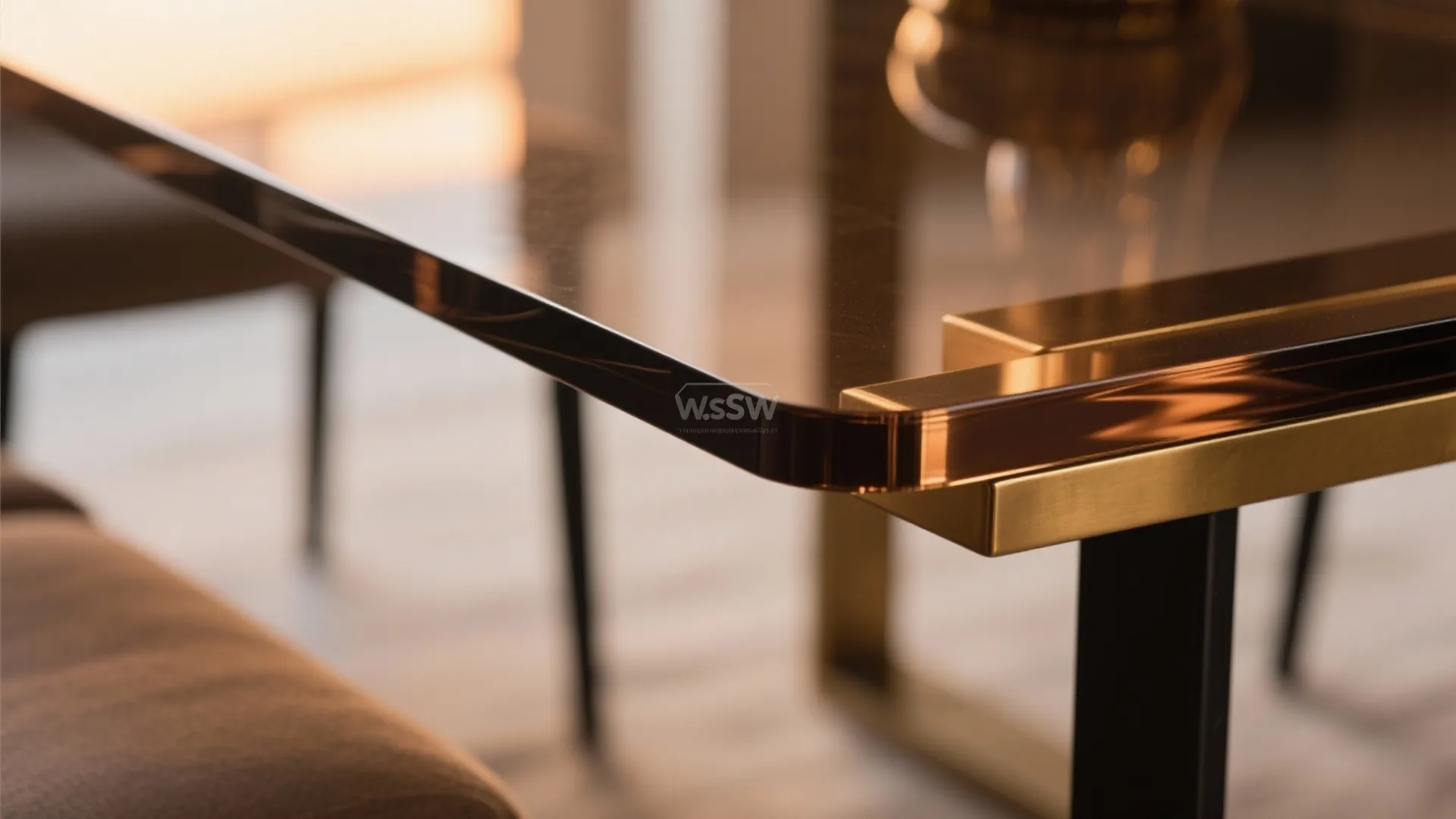 Close up of a brown glass table with gold metal corner and black metal legs