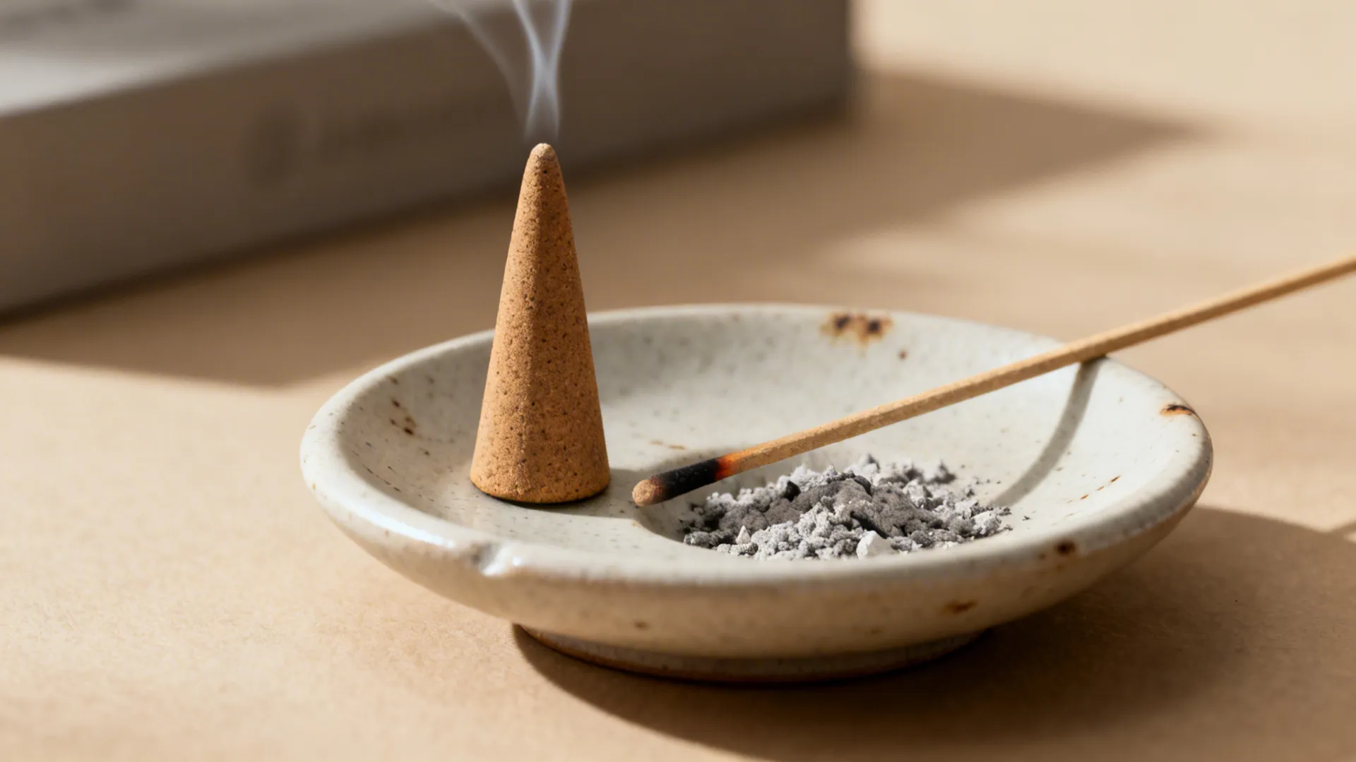 Close-up of a resin-free incense cone and smokeless stick on a ceramic holder with contained ash.