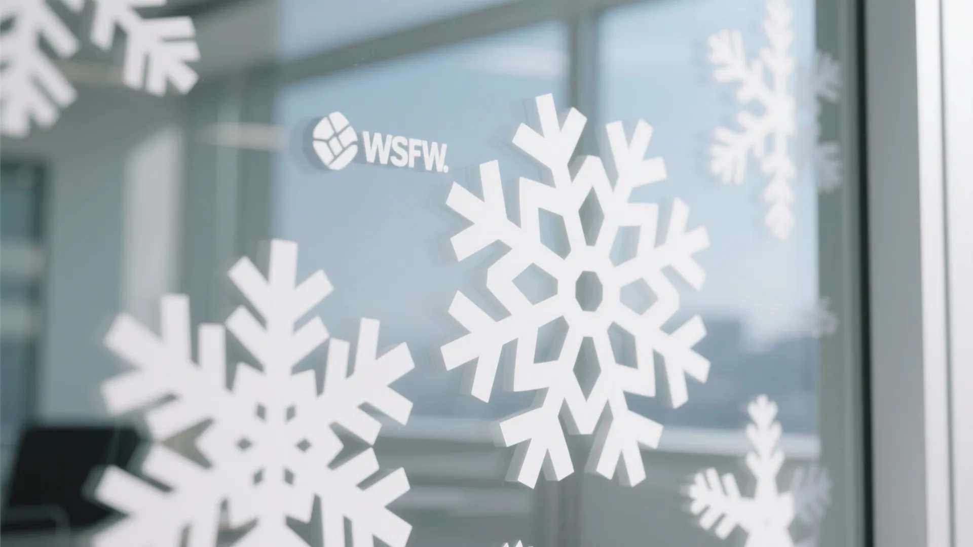Large white snowflake stickers attached to an office glass window for winter seasonal interior decoration