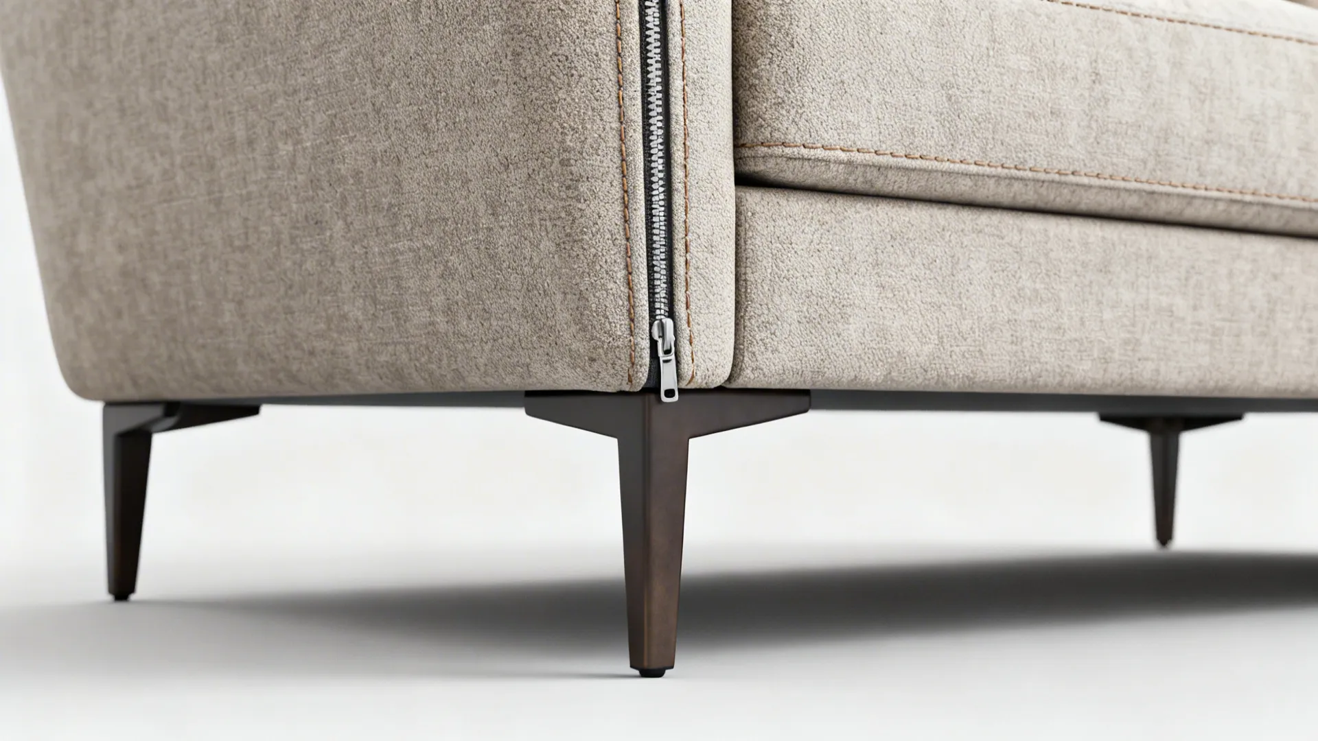 Close-up of an L-shaped sofa corner, removable cover zipper and elevated leg for easy cleaning.