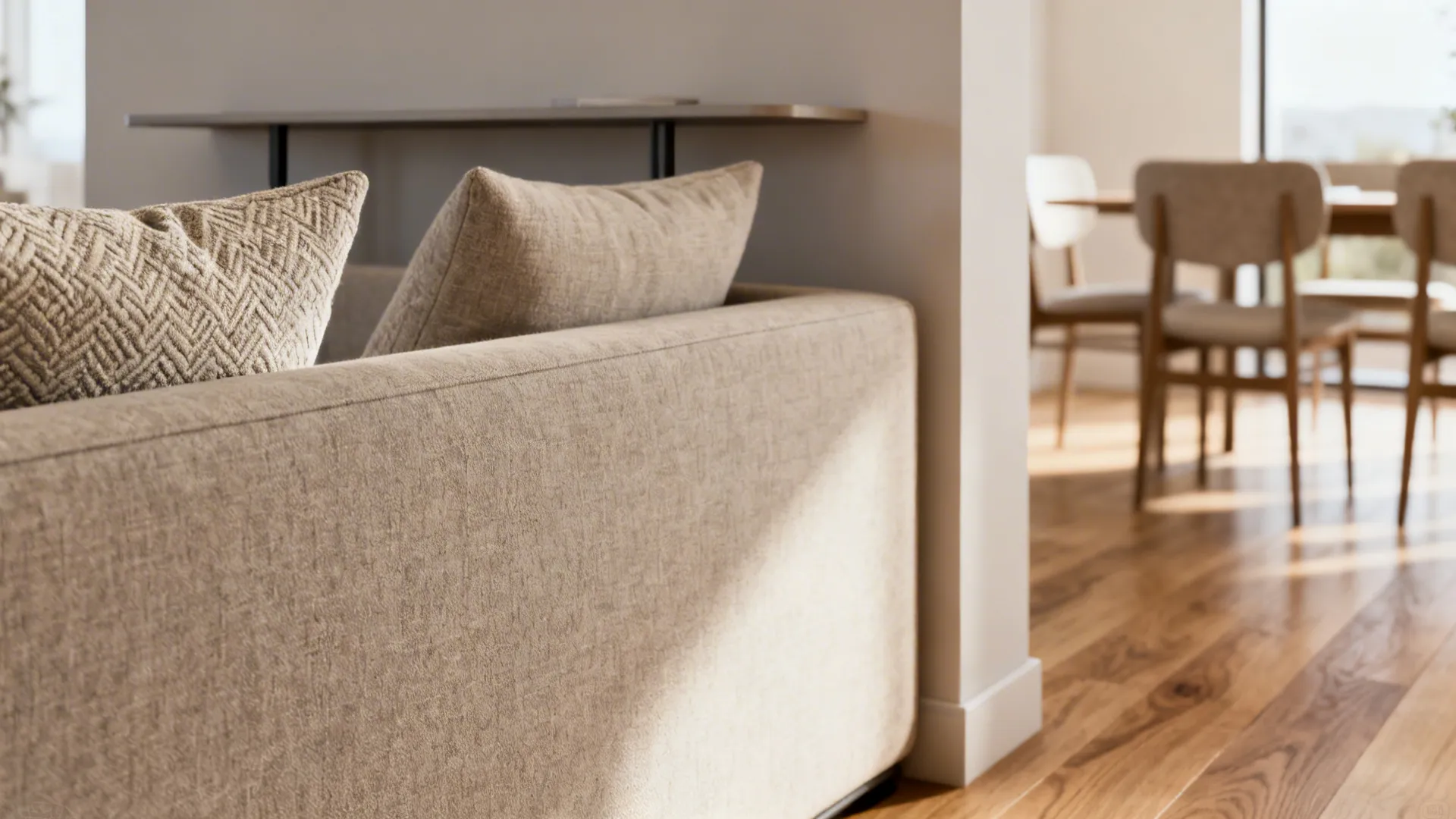 Close up of a beige sofa acting as a divider between living and dining room areas
