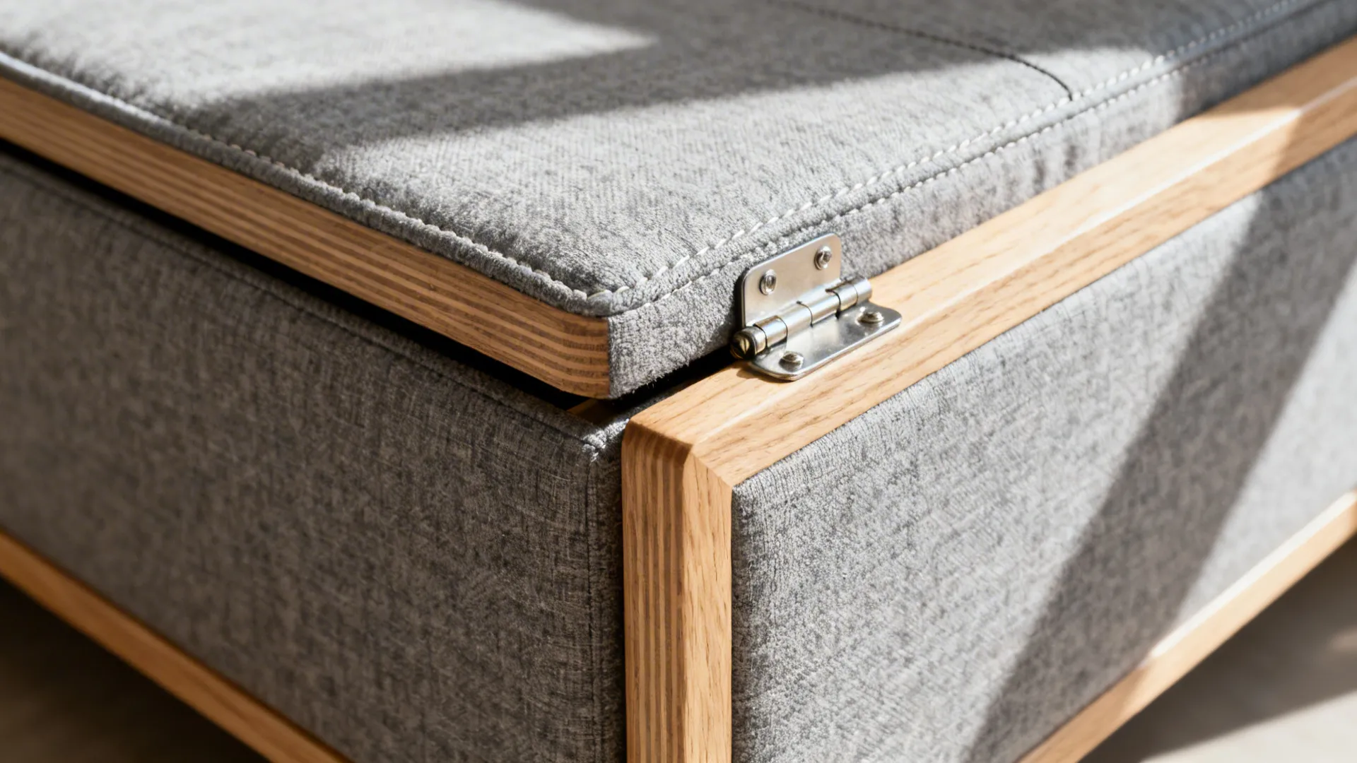 Close-up of storage chaise hinge and tight-weave upholstery on a slim sofa.