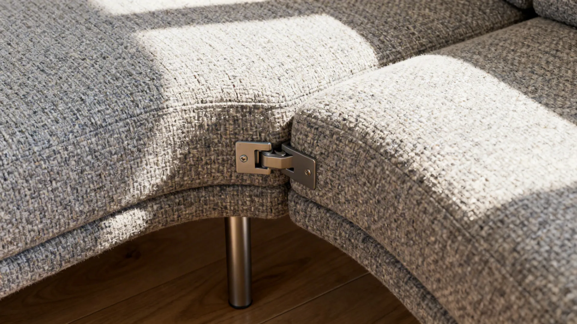 Macro of curved sofa modules showing locking brackets and boucle fabric texture.