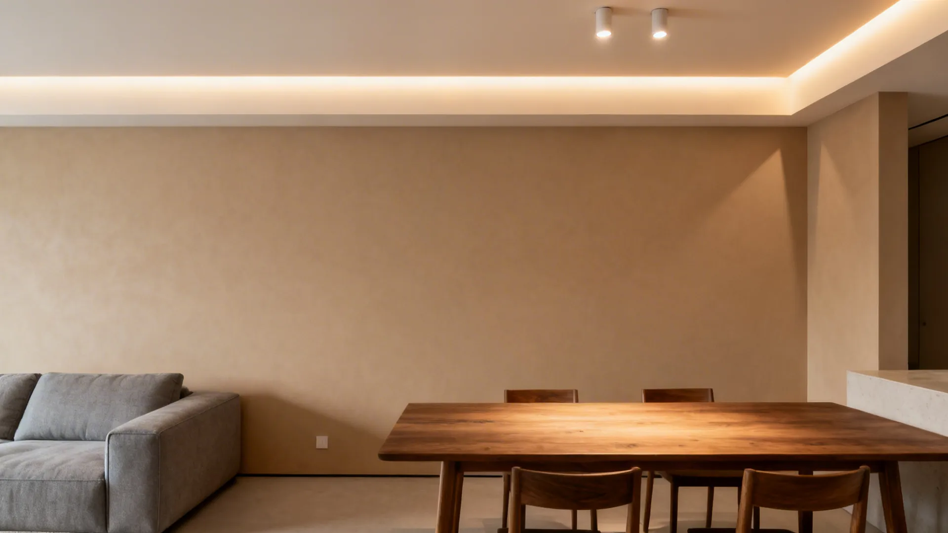 Living–dining room with a shallow perimeter cove and warm layered lighting over the dining area.