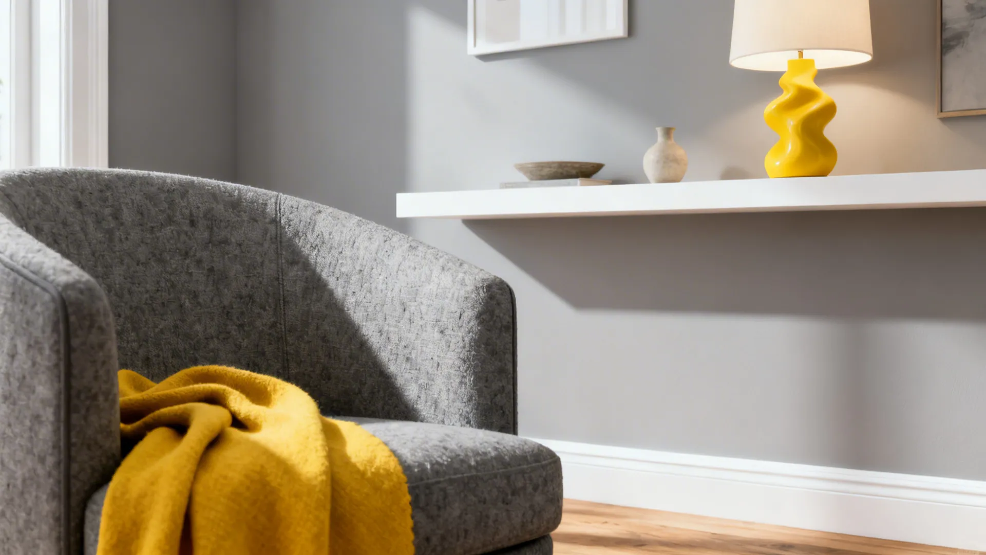 Grey armchair with yellow blanket next to white wall shelf holding a yellow table lamp