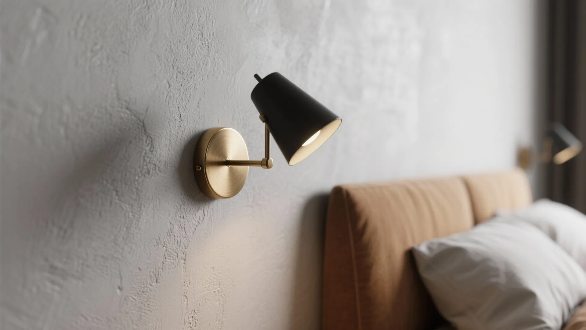 Brushed brass sconce and matte black lamp in gray and tan bedroom reflecting soft daylight