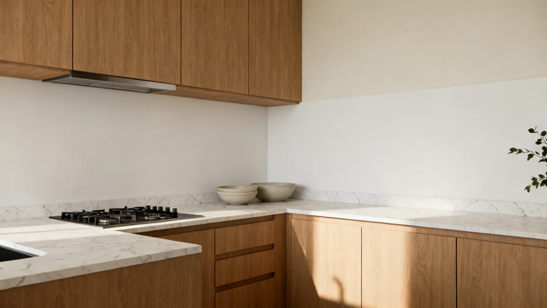 Minimalist kitchen with light wood cabinets, white marble countertops, gas stove, and bright natural light