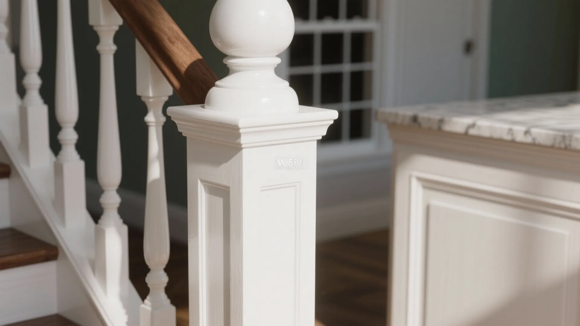 Close up of a white wooden staircase post and handrail next to a kitchen cabinet