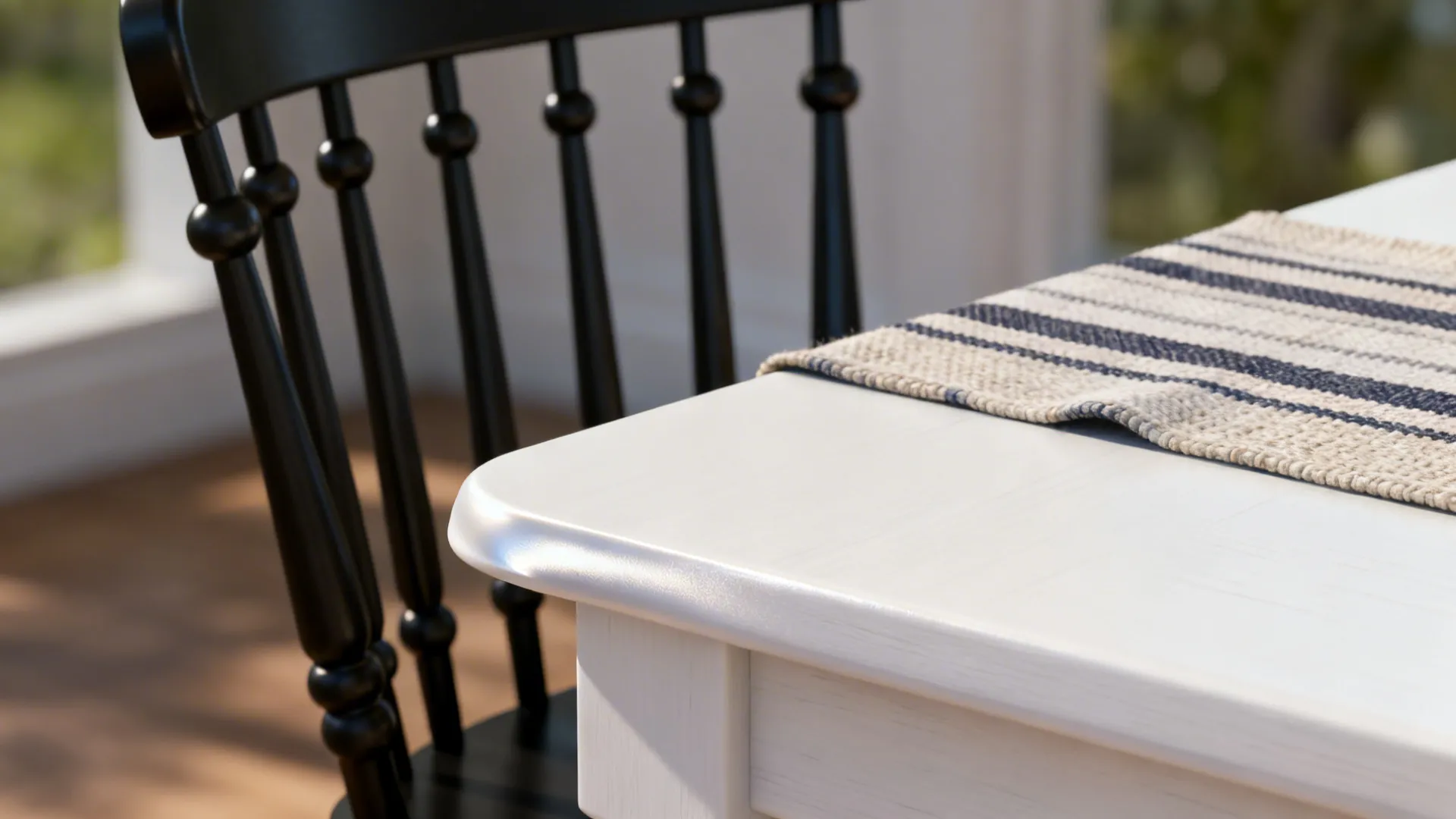 Close up view of a white table corner with striped cloth and a black chair