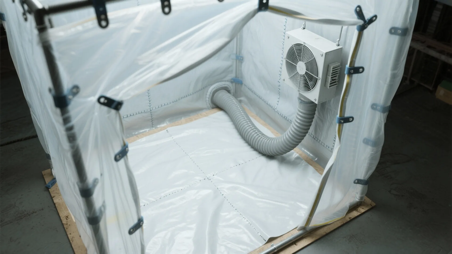 Portable painting booth with plastic walls, fan unit, exhaust pipe, metal frame, and wooden base