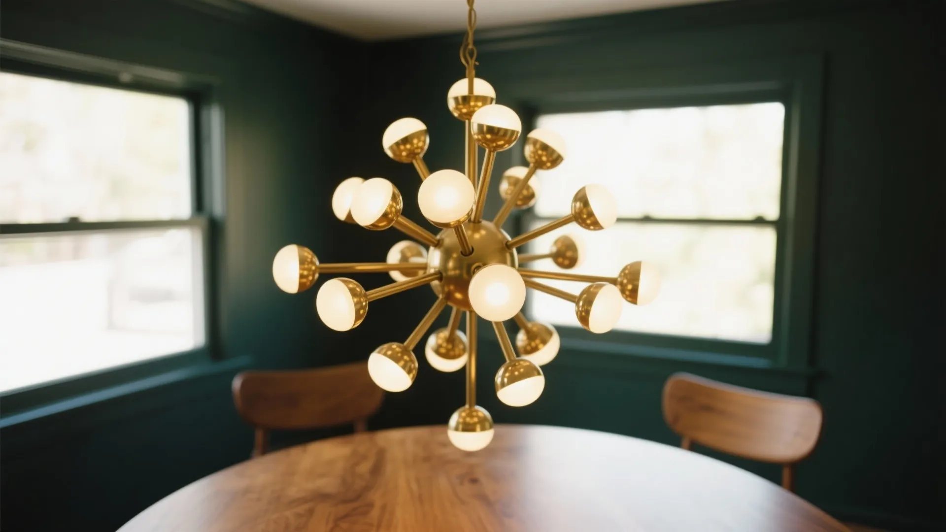 Modern gold starburst ceiling light hanging above a wooden dining table in a dark room