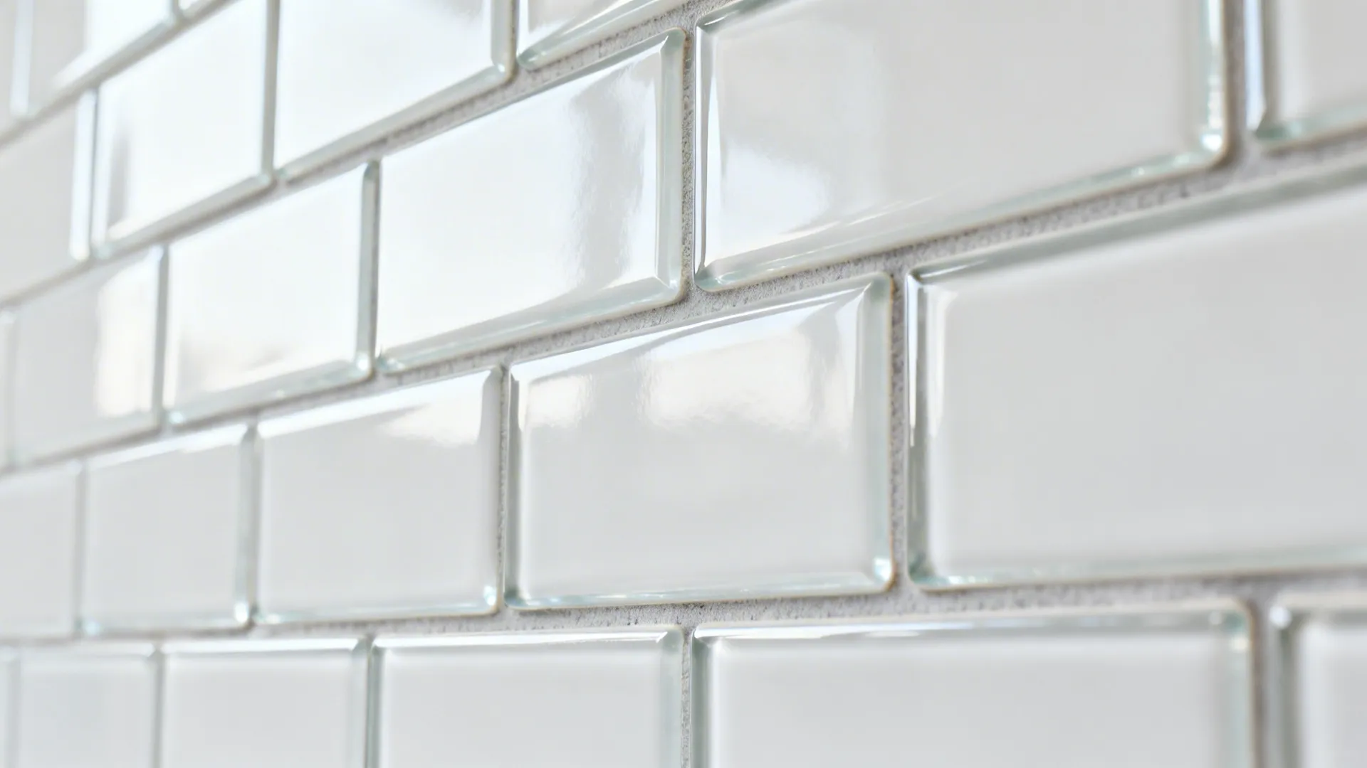 Macro of glossy stacked glass subway tiles with light gray grout.