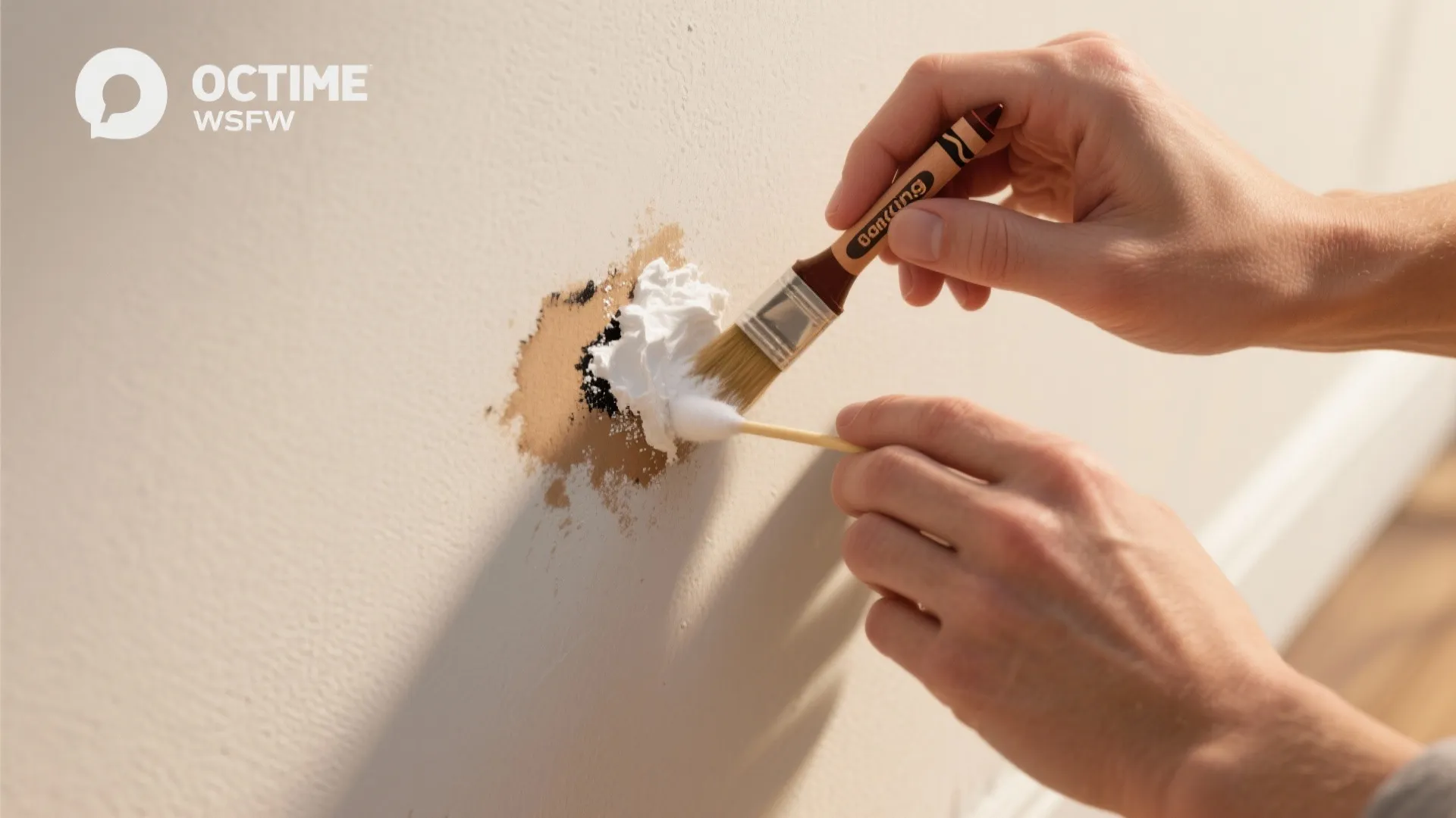 Hands using small brush and cotton swab to clean brown stain on a white wall
