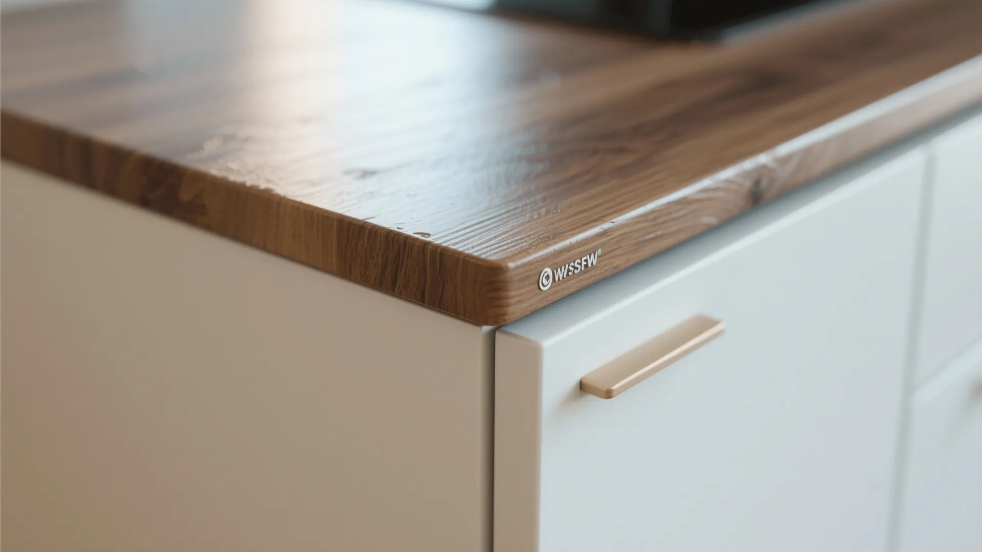 Close up of dark wood countertop on white kitchen cabinets with a gold door handle
