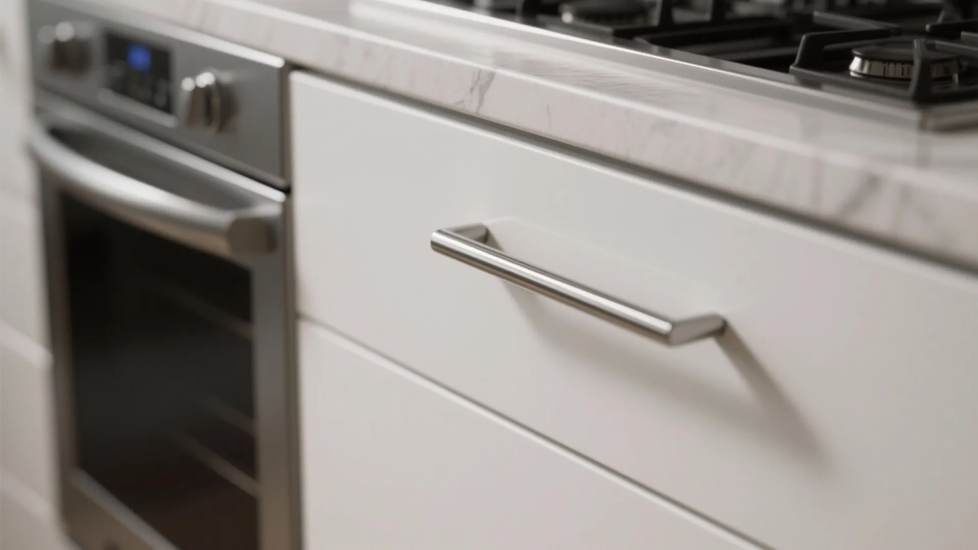 Close up of a silver metal cabinet handle on a white drawer near an oven