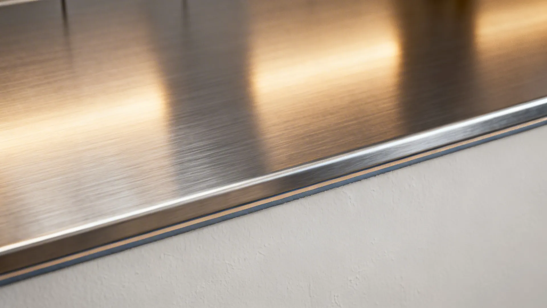 Macro shot showing the brushed texture and reflection of a stainless steel kitchen countertop surface