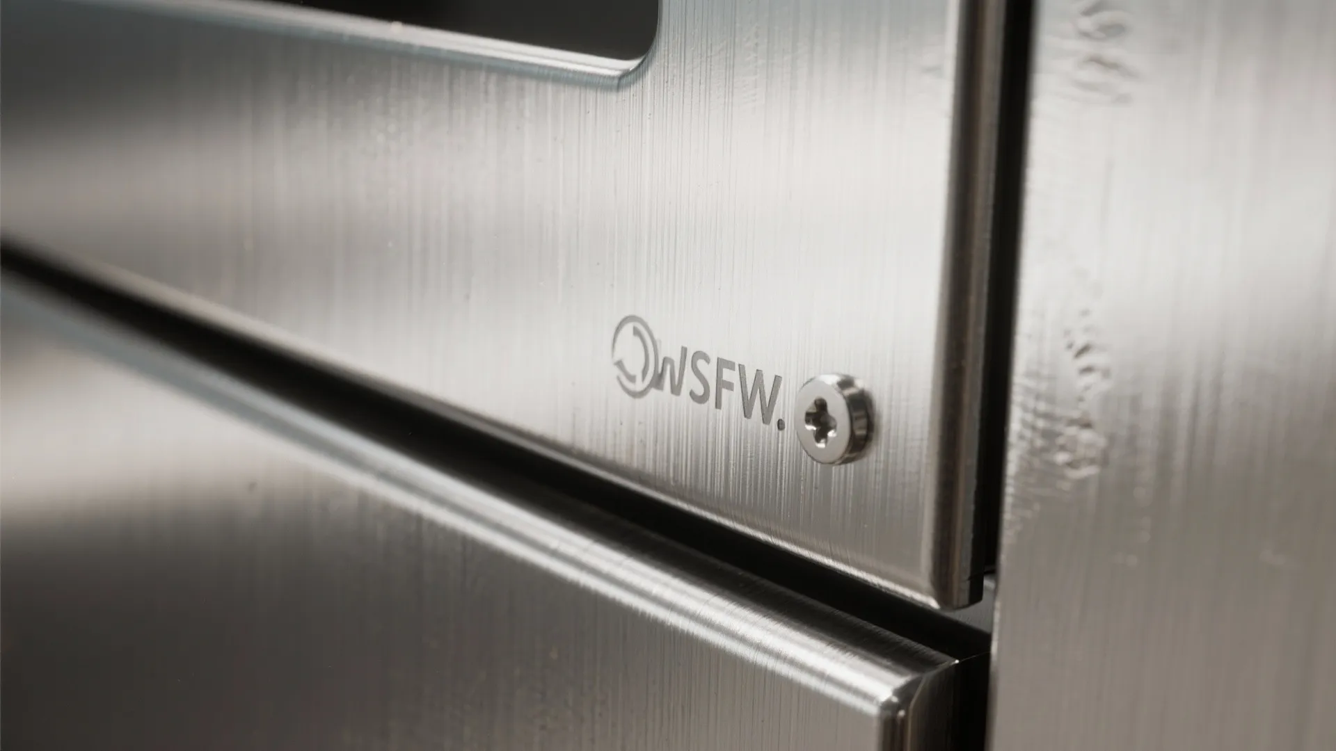 Close up view of a brushed stainless steel surface with a small screw and logo