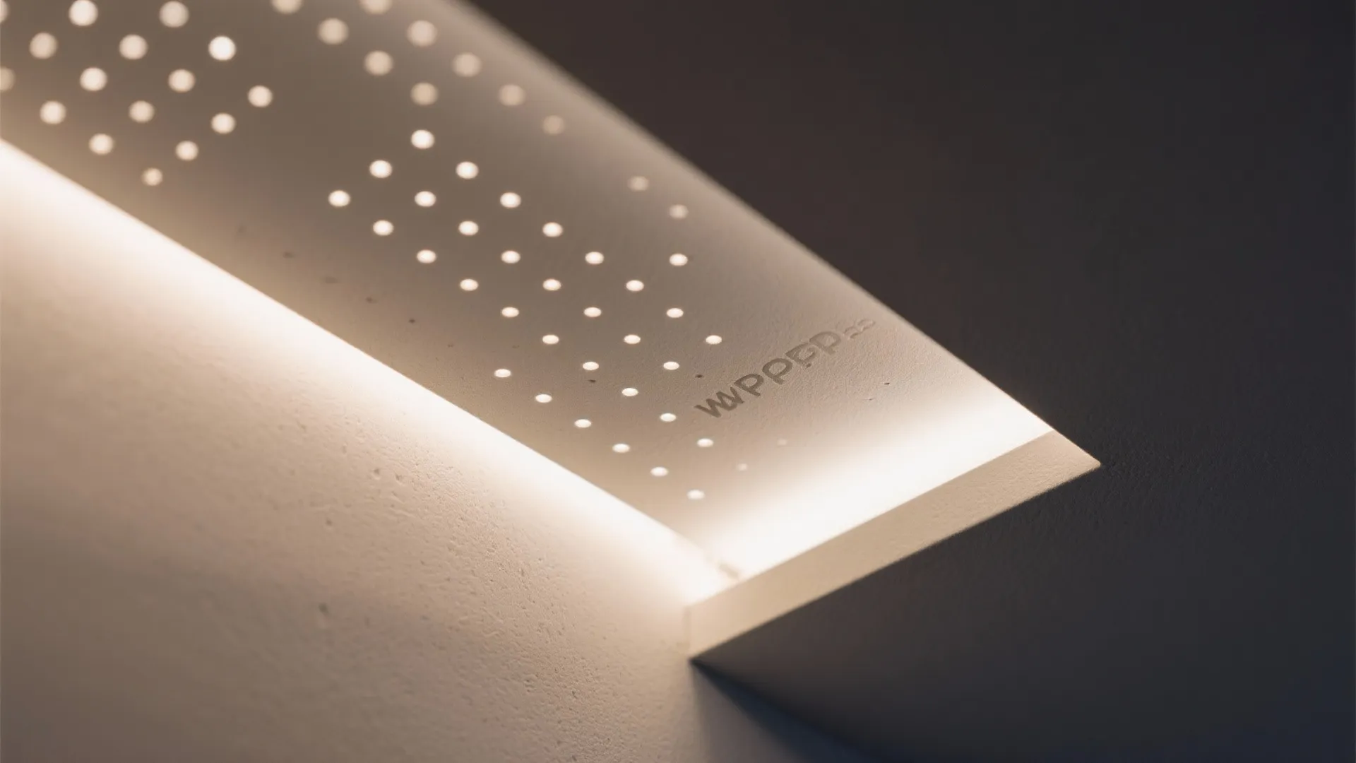 Close up view of a white ceiling light fixture with many small round perforated holes