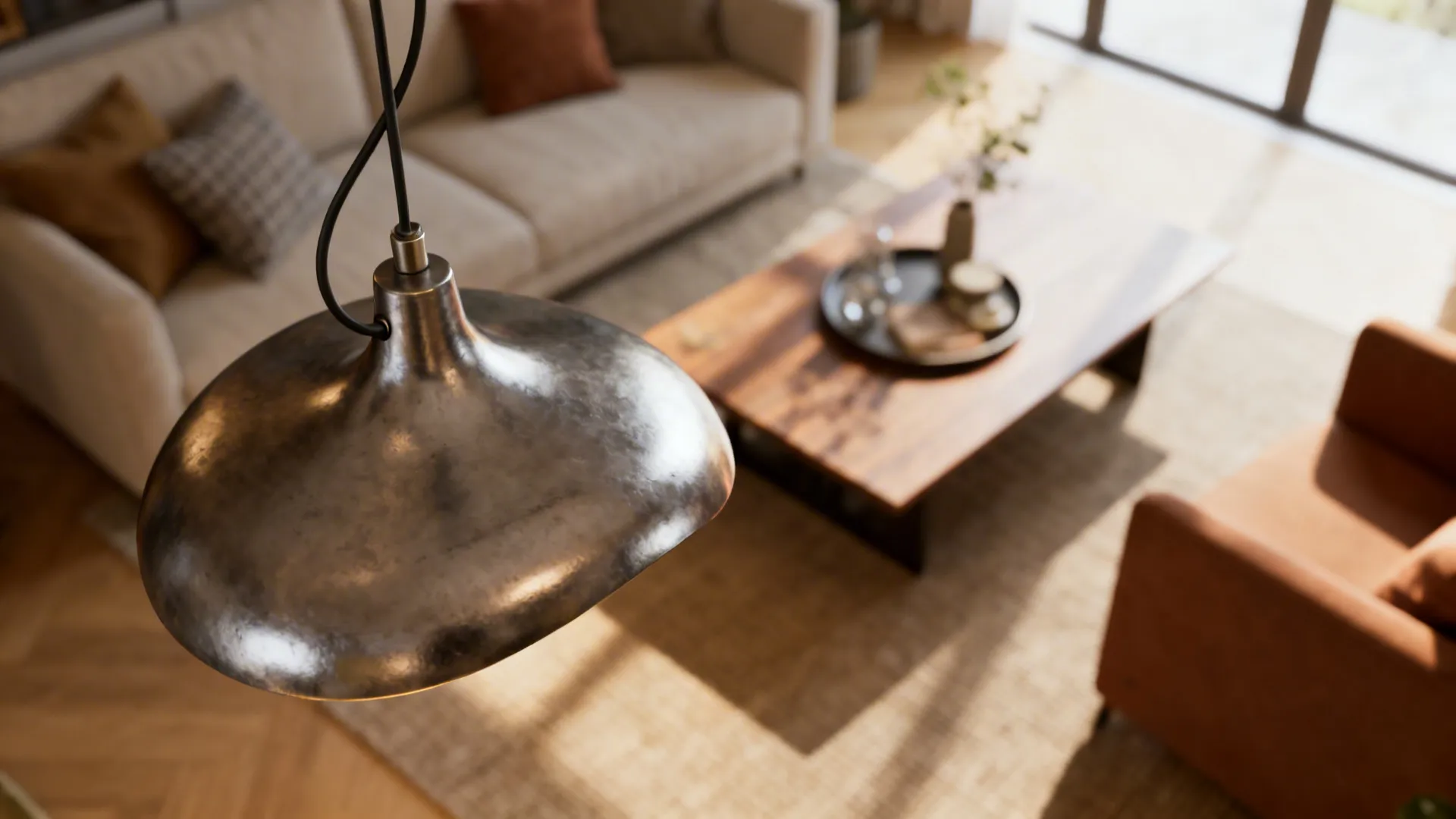 Close-up of a sculptural metal pendant light with adjustable cable over a living room table.