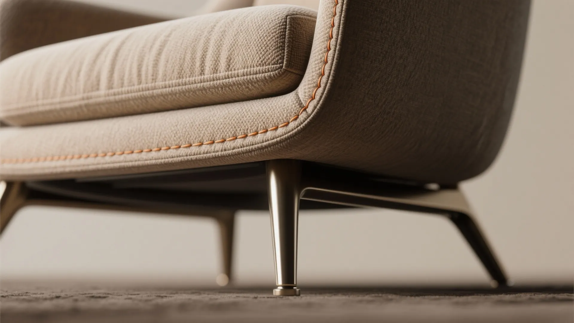 Close-up of a modern sofa with orange stitching detail and sturdy metal legs on carpet