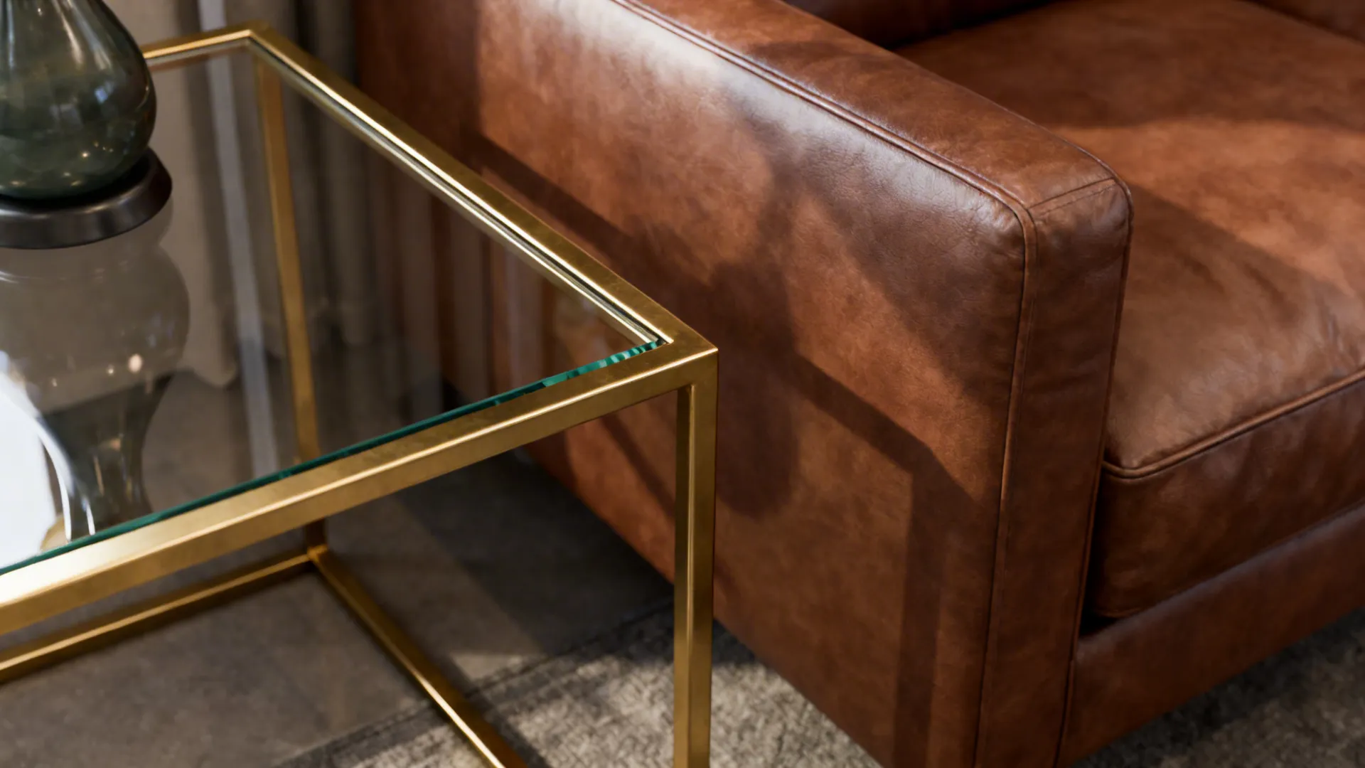 Slim brass-trimmed coffee table and glass console near a brown leather sofa, showing scale and reflective contrast.