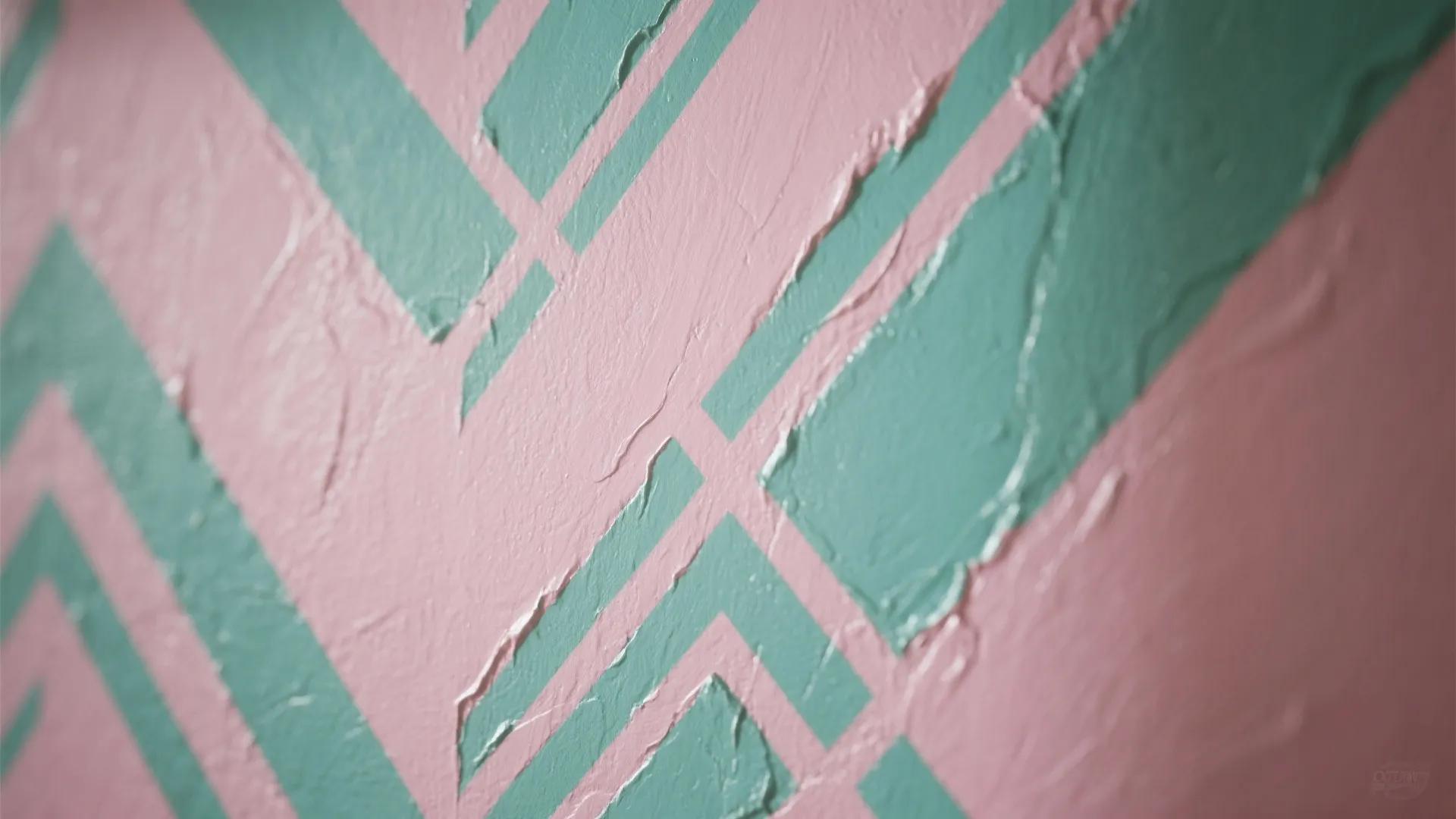 Close-up of a geometric stenciled wall in pink and green showing paint texture and crisp edges.