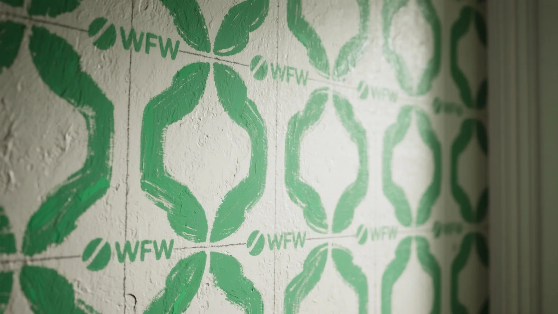 Macro view of a two-tone green stenciled wall pattern showing handmade texture and crisp edges.
