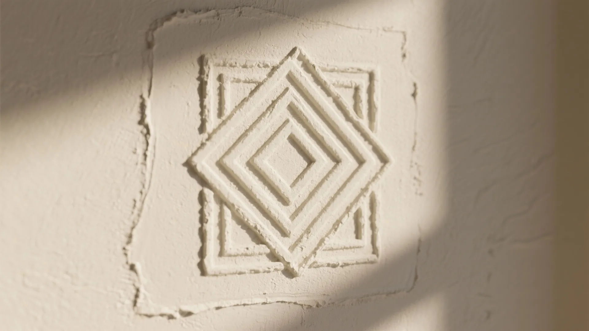 A decorative square plaster wall panel with geometric patterns and soft sunlight shadow on it