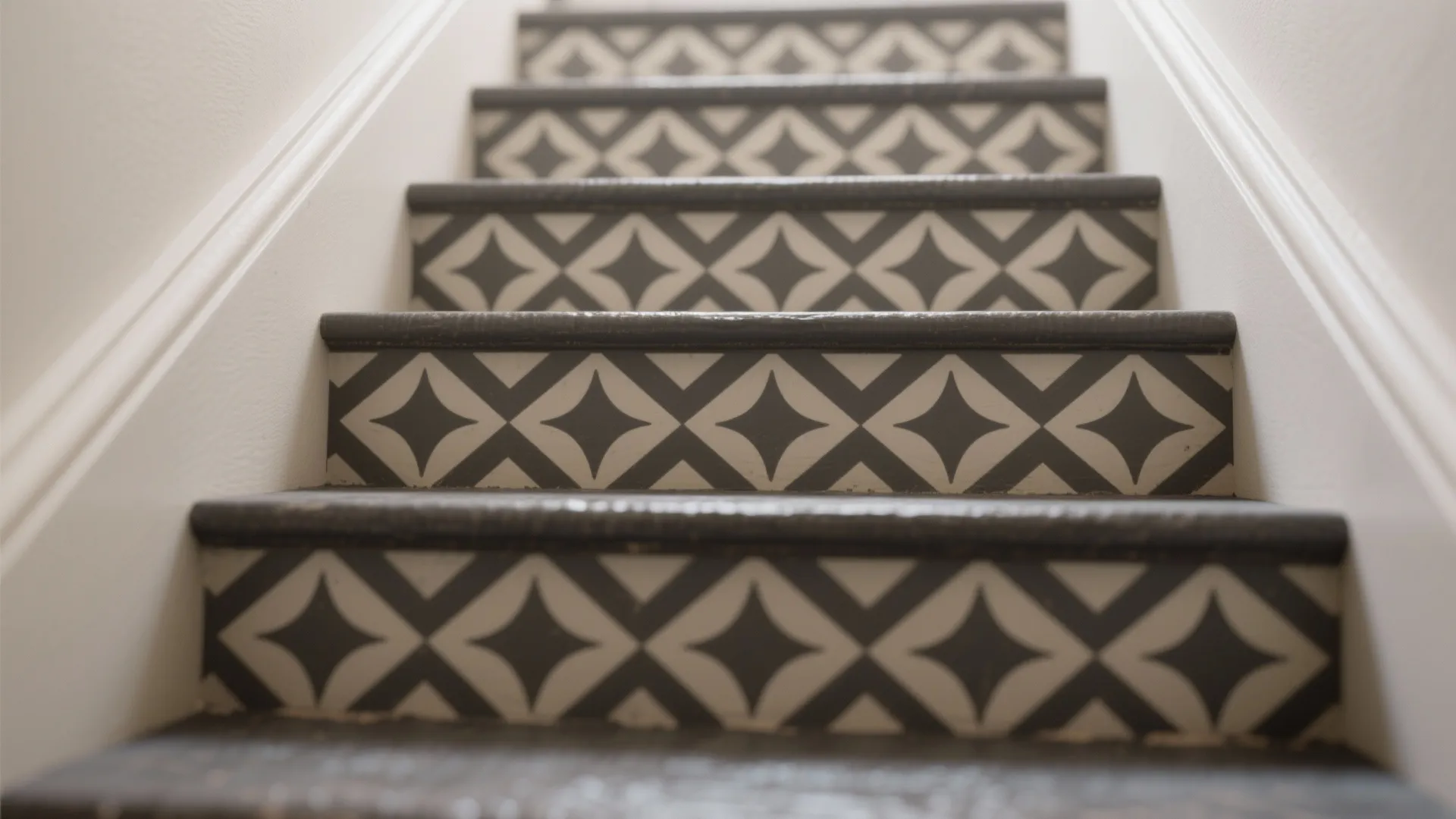 Close up of indoor stairs featuring grey and white geometric diamond pattern stickers on risers
