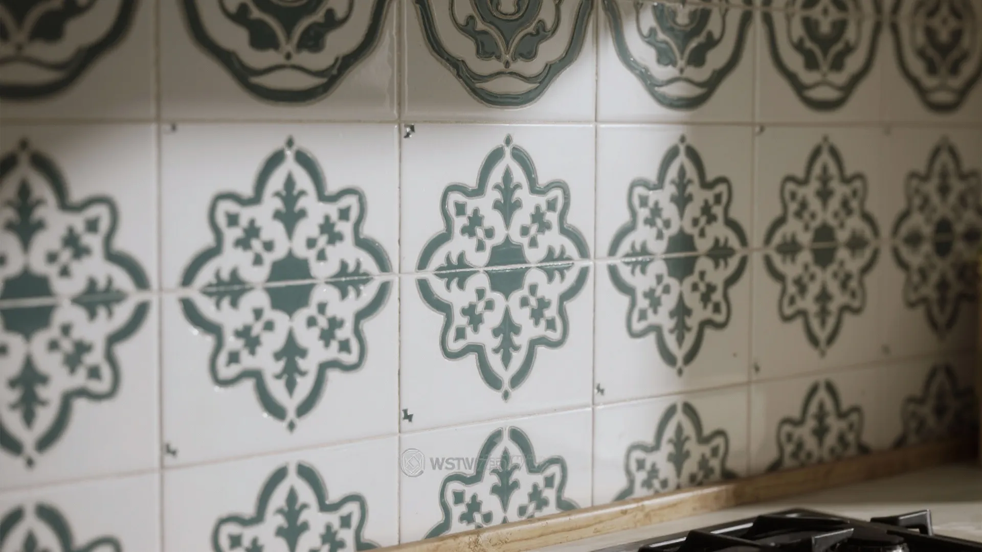Close up view of white wall tiles decorated with green flower patterns in a kitchen