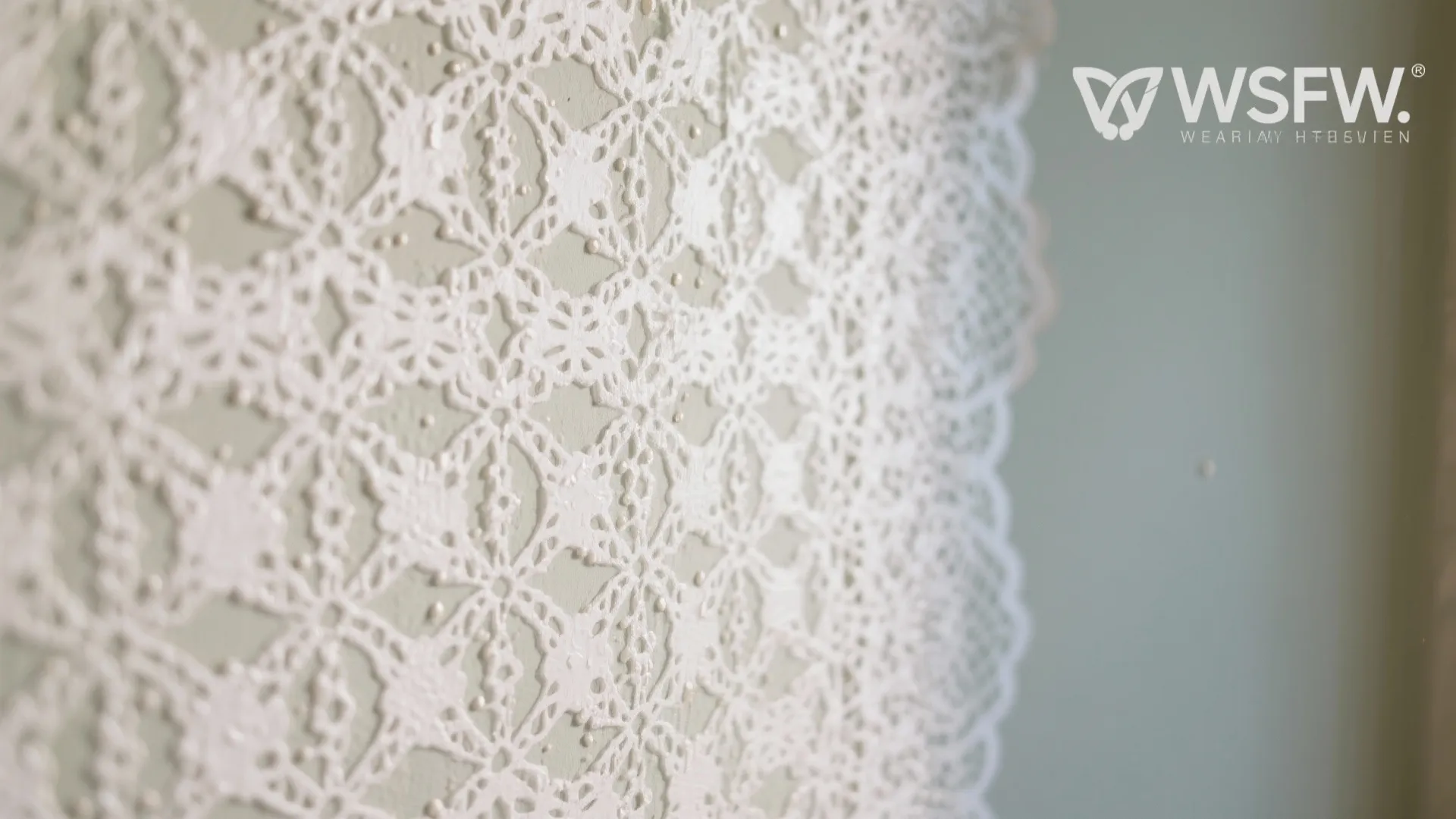 Close up view of white lace pattern wall texture on light green surface with natural lighting