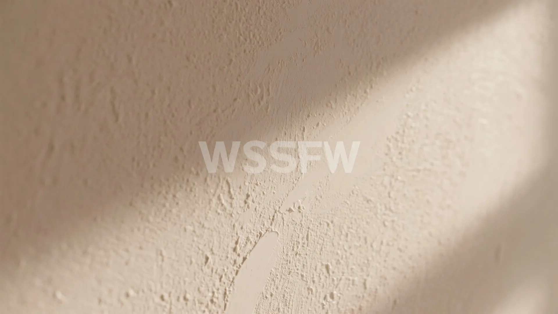 Close up view of beige textured wall with diagonal shadows and rough plaster surface finish