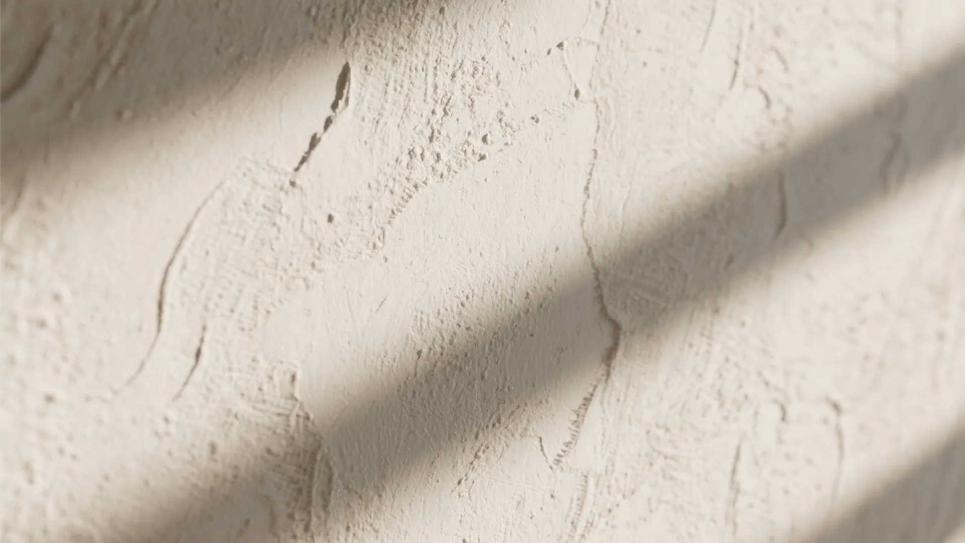 Close up view of textured beige wall surface with soft shadows from sunlight hitting the wall