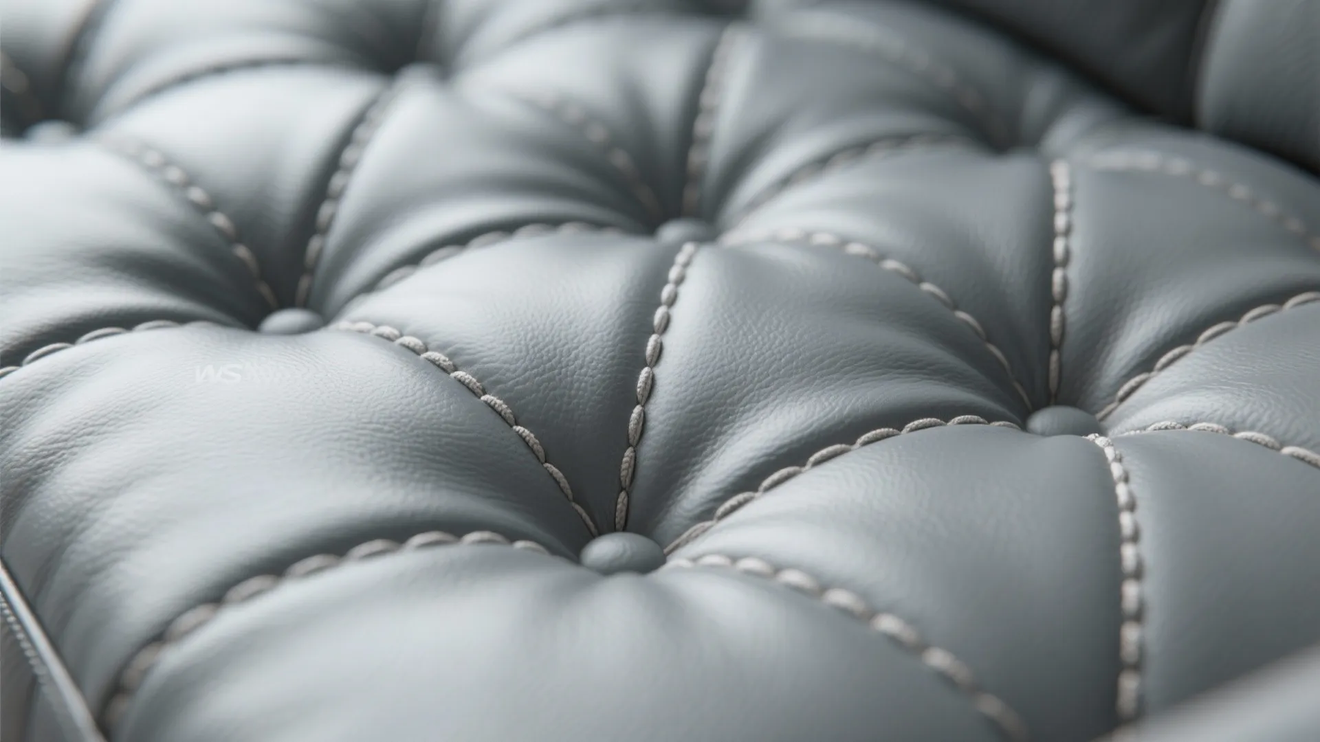 Close up of grey leather furniture surface with diamond stitching pattern and small round buttons