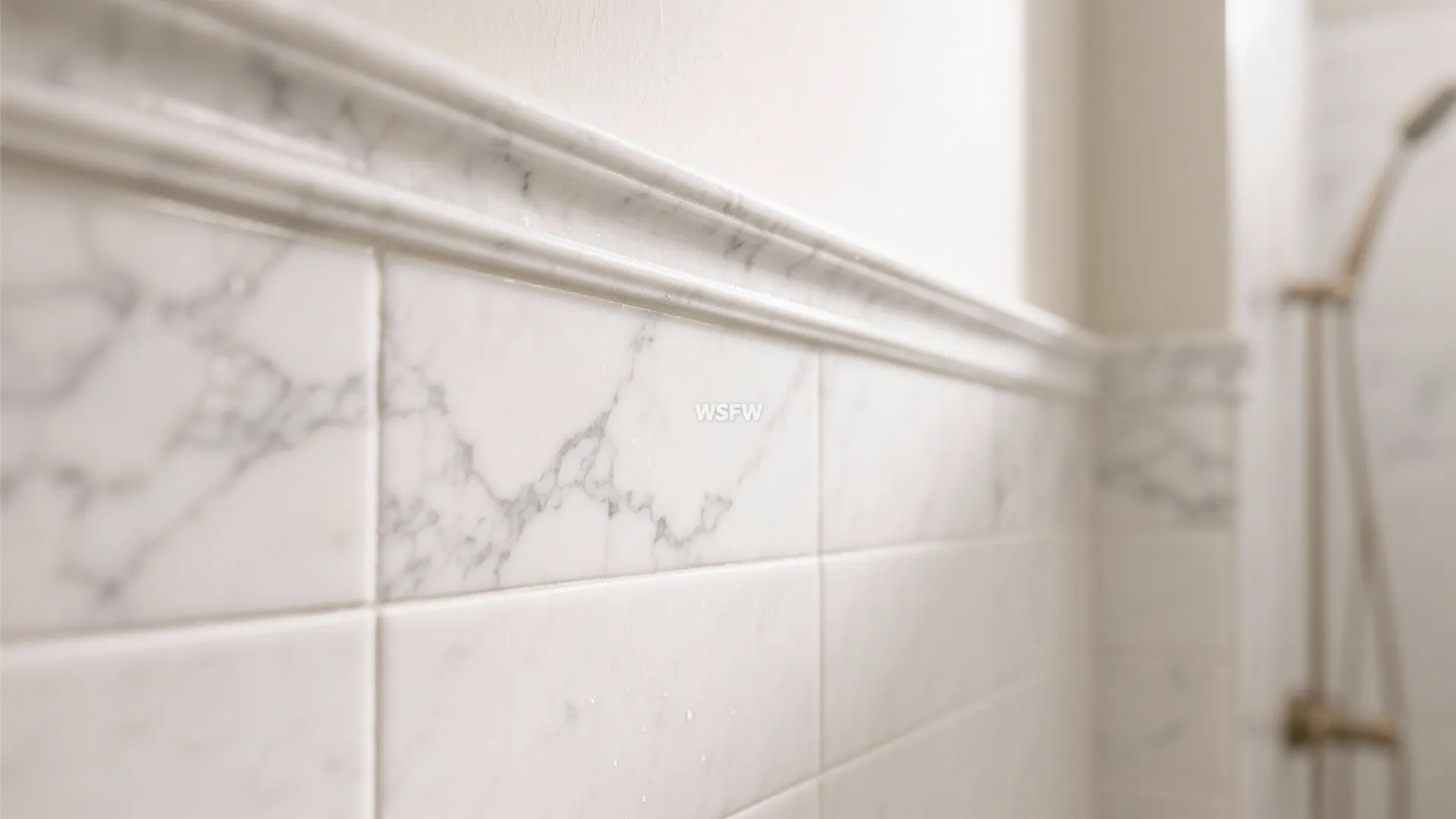 Macro detail of a veined marble chair rail above honed white tile with a crisp grout line.
