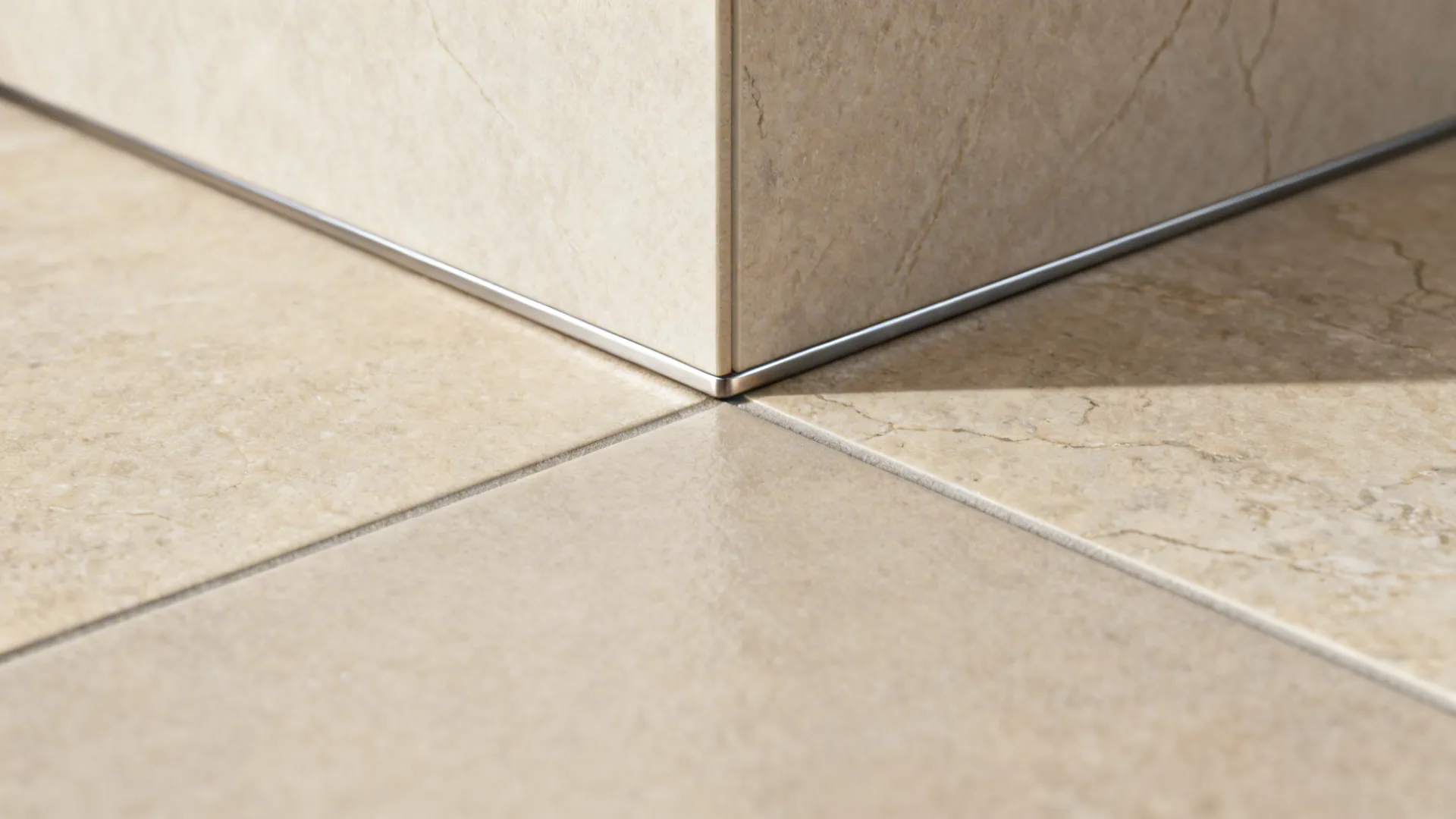 Macro of stone-look porcelain floor and honed wall meeting with a clean metal trim