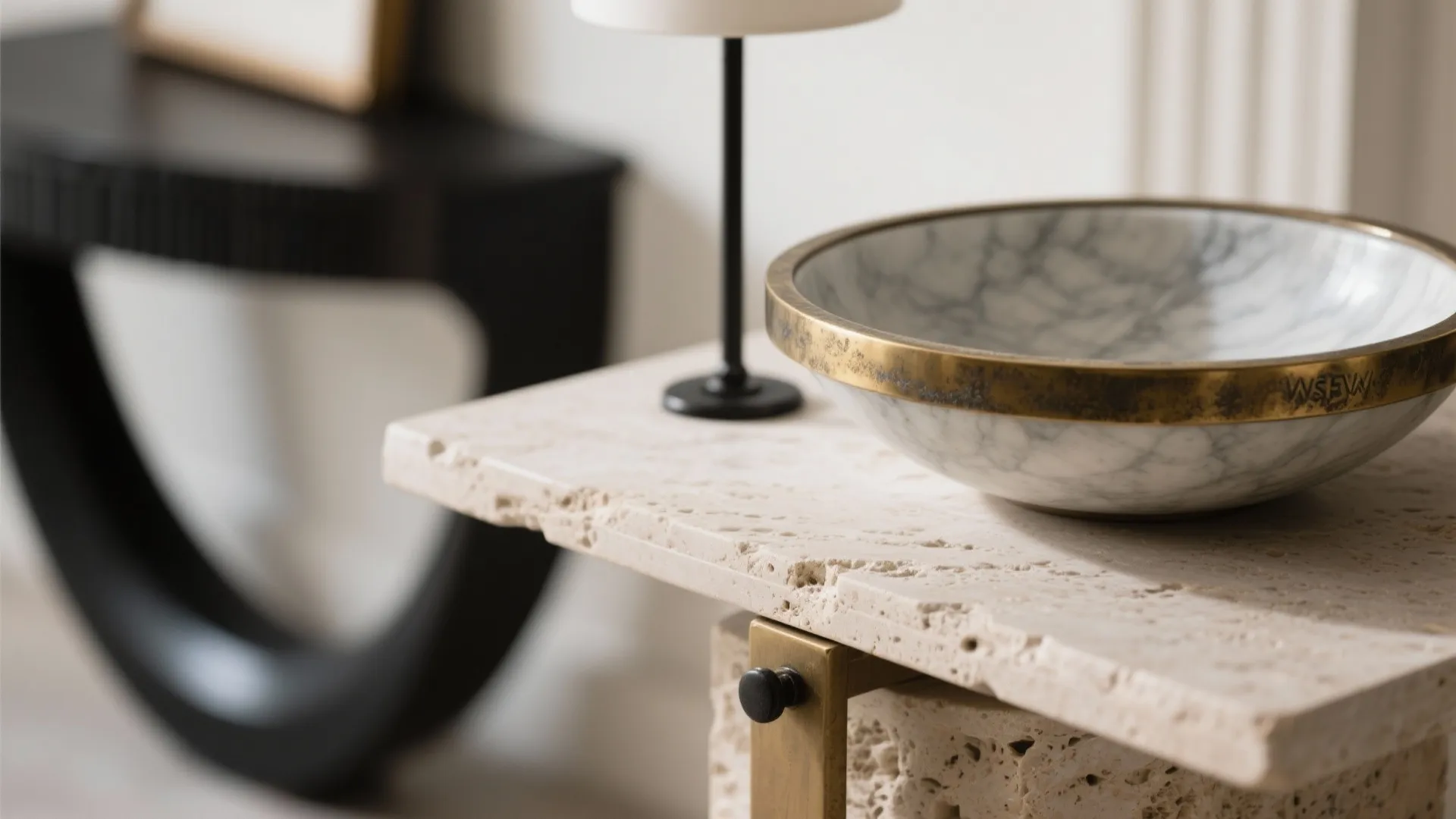 Close up of stone table with marble bowl brass trim and small black table lamp