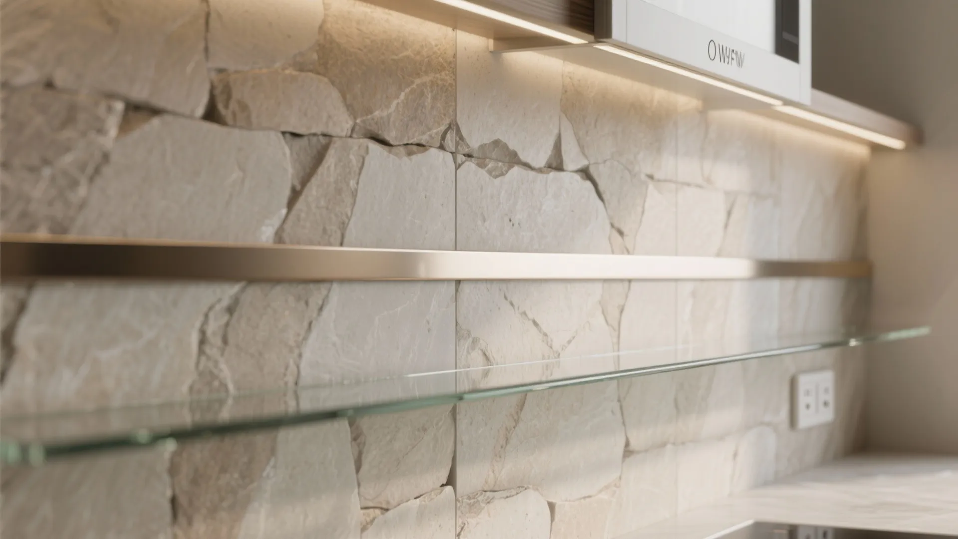 Close-up of a honed stone backsplash with a thin polished metal and glass accent strip aligned near an outlet.