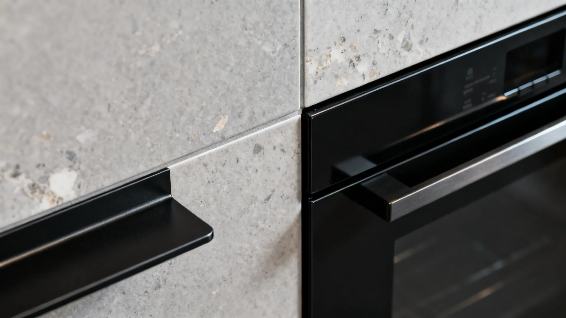 Close-up of matte stone-look porcelain tile with satin black steel shelf and appliance panel.