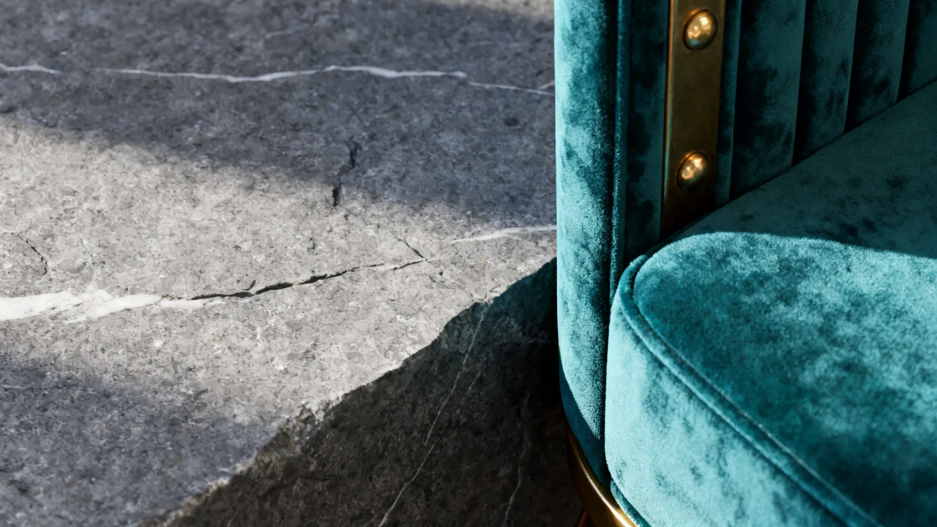 Close-up of cool gray stone next to teal velvet upholstery and brass trim