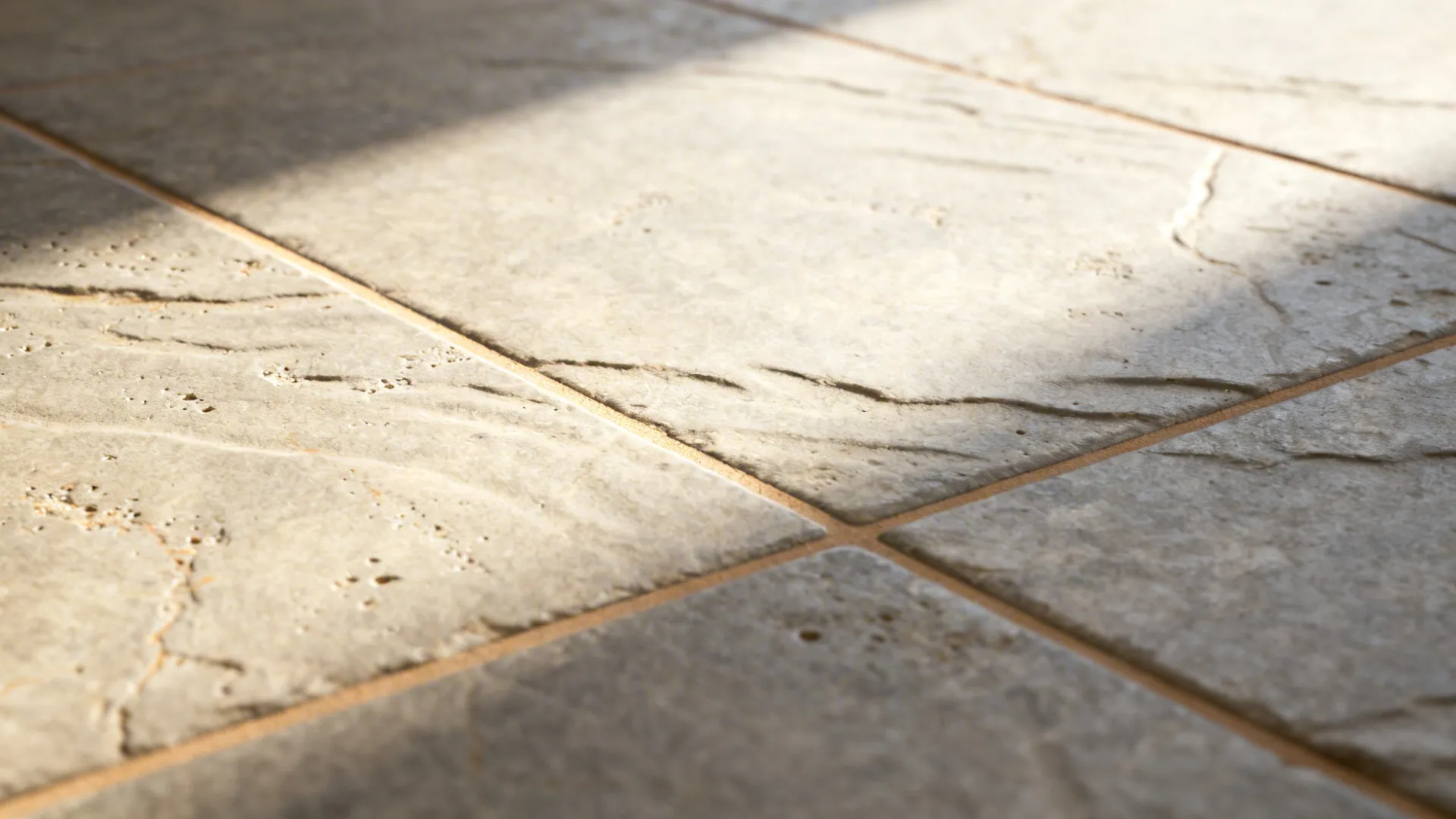 Macro of warm taupe stone-look tile with color-matched grout lines.
