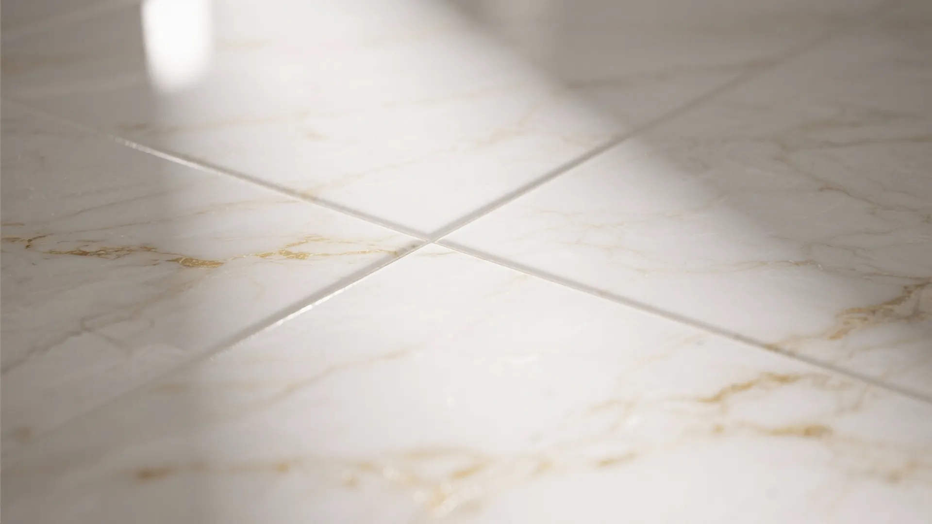 Macro of white porcelain tile with subtle warm veining and tight grout line.