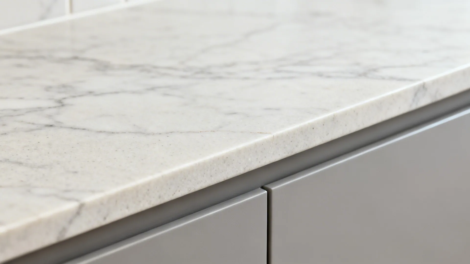 Macro of honed stone backsplash veining beside a soft-grey cabinet.