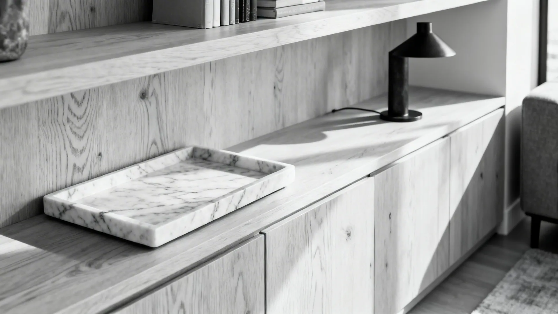 White oak shelving with a honed marble tray and a blackened steel lamp in a monochrome scheme.